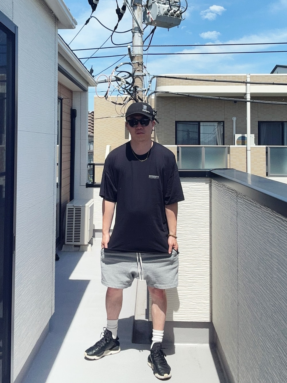 ブラック系のスニーカー、ブラック系のTシャツ/カットソー、グレー系のパンツを着用したメンズの夏コーディネートの2枚目の写真