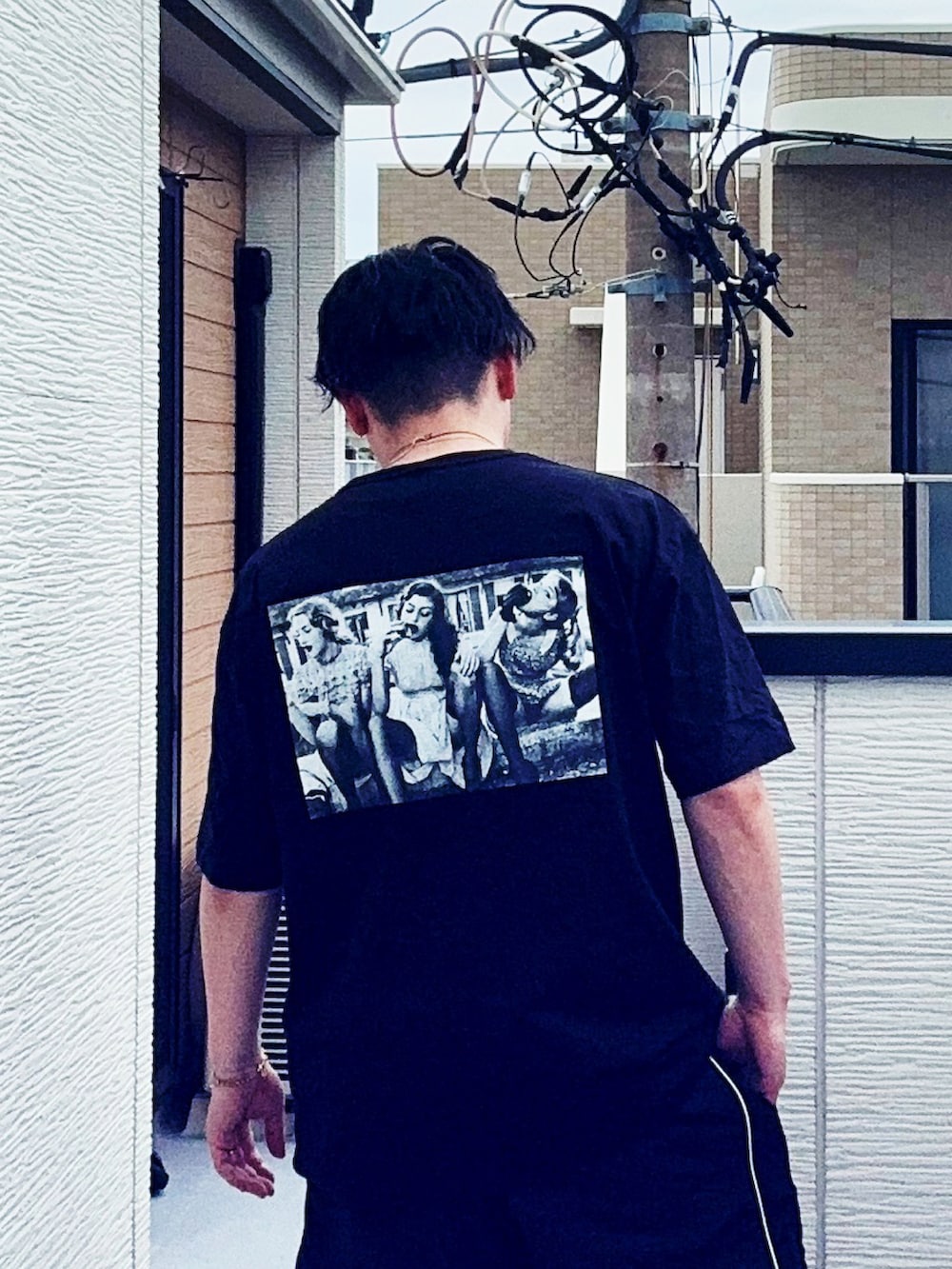 ブラック系のスニーカー、ブラック系のTシャツ/カットソー、ブラック系のパンツを着用したメンズの春コーディネートの3枚目の写真