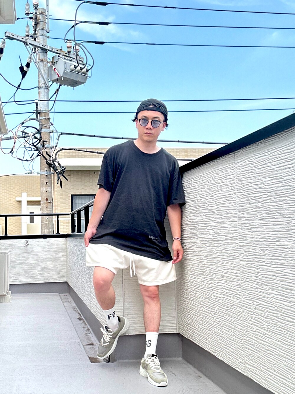 グレー系のスニーカー、ブラック系のTシャツ/カットソー、ホワイト系のスウェットパンツを着用したメンズの夏コーディネートの2枚目の写真