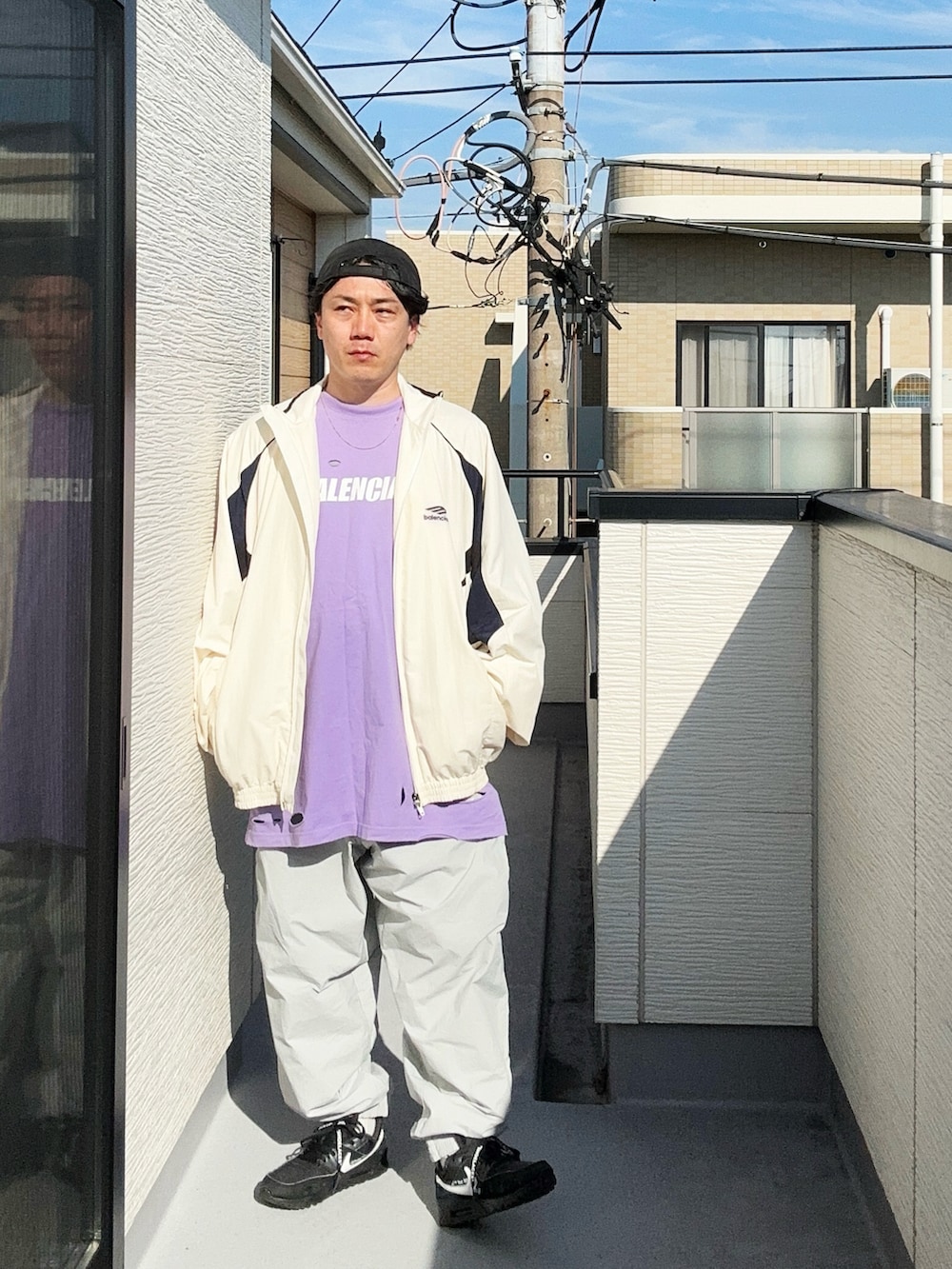 グレー系のその他パンツ、パープル系のTシャツ/カットソー、ホワイト系のナイロンジャケットを着用したメンズの秋コーディネートの4枚目の写真