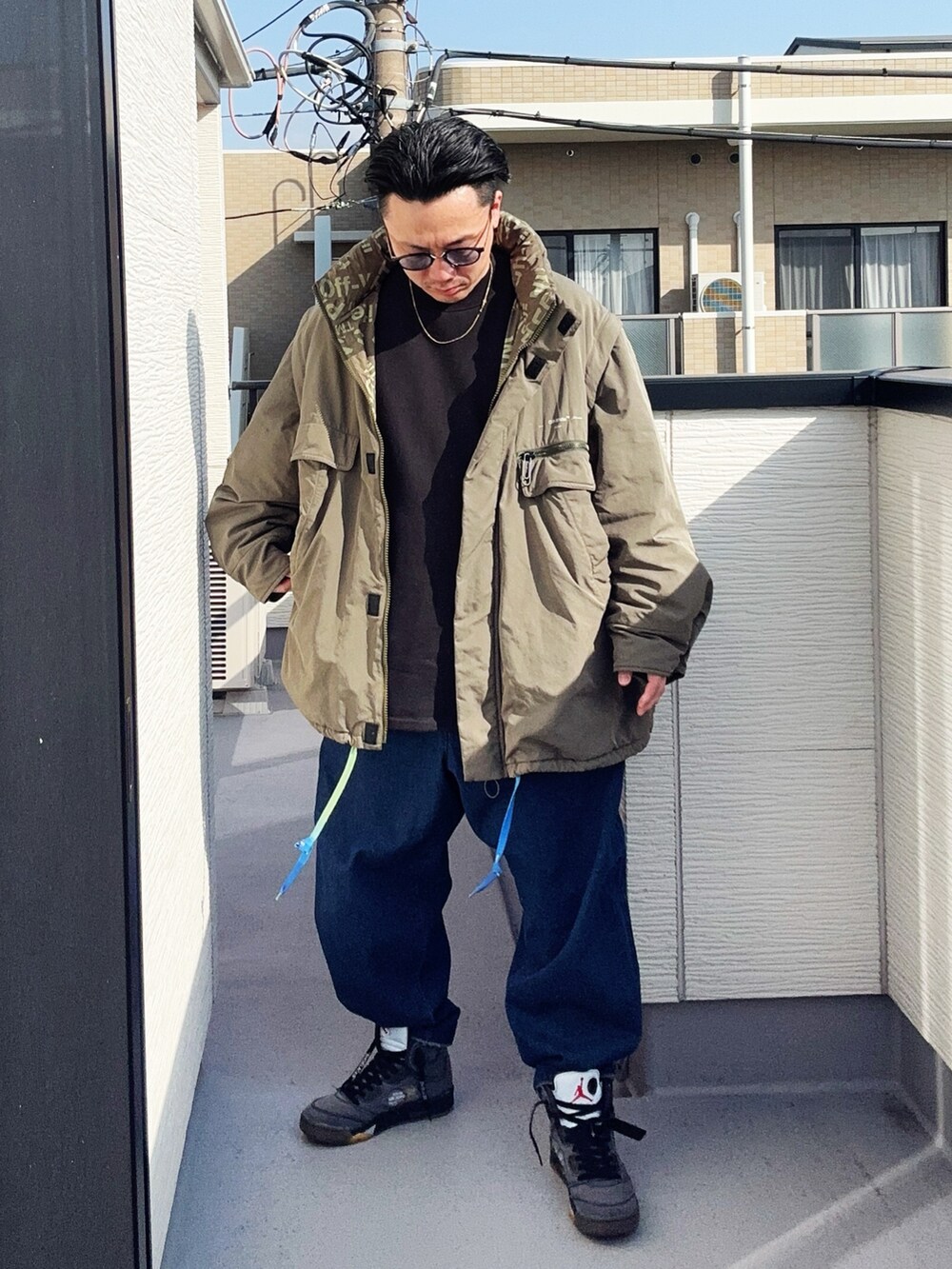 ブルー系のデニムパンツ、ブラック系のスウェット、グリーン系のミリタリージャケットを着用したメンズの冬コーディネートの2枚目の写真