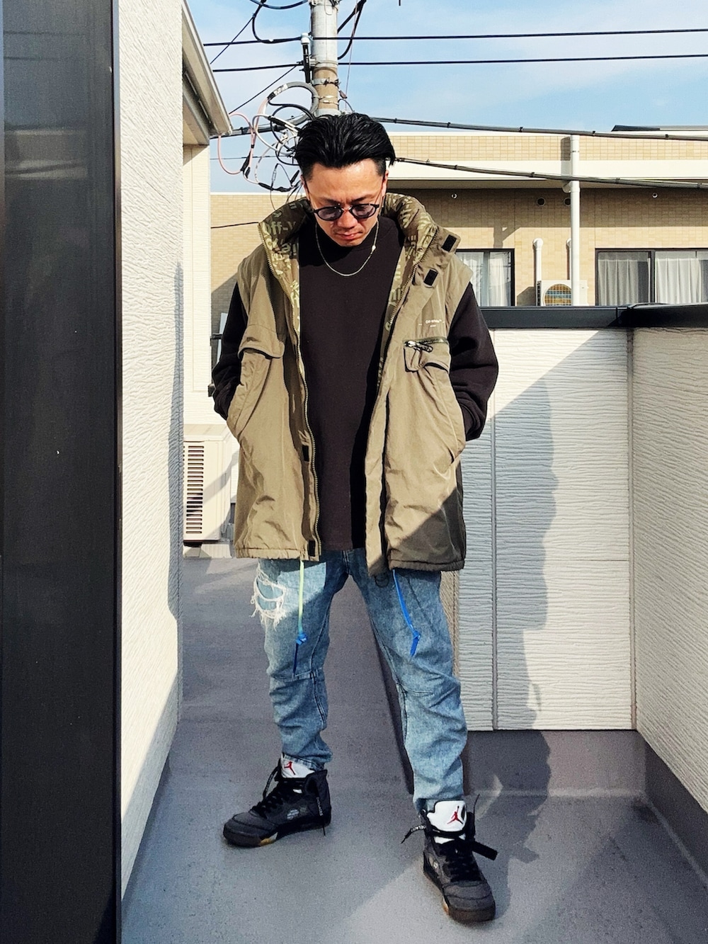 ブラック系のスウェット、ブルー系のデニムパンツ、グリーン系のミリタリージャケットを着用したメンズの冬コーディネートの5枚目の写真