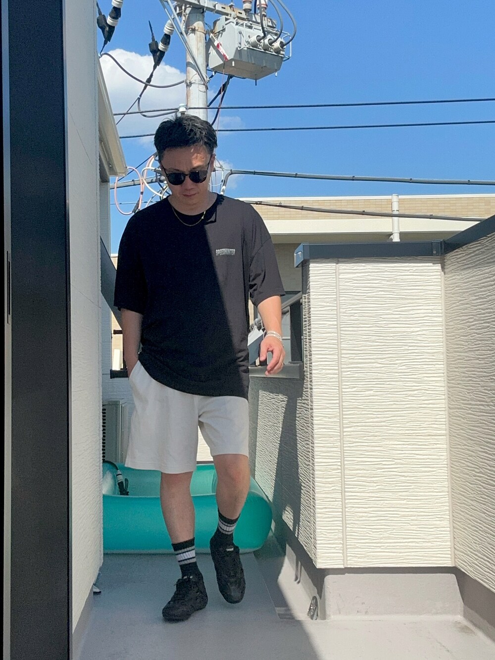 ブラック系のTシャツ/カットソー、ホワイト系のパンツ、ブラック系のシューズを着用したメンズの夏コーディネートの3枚目の写真