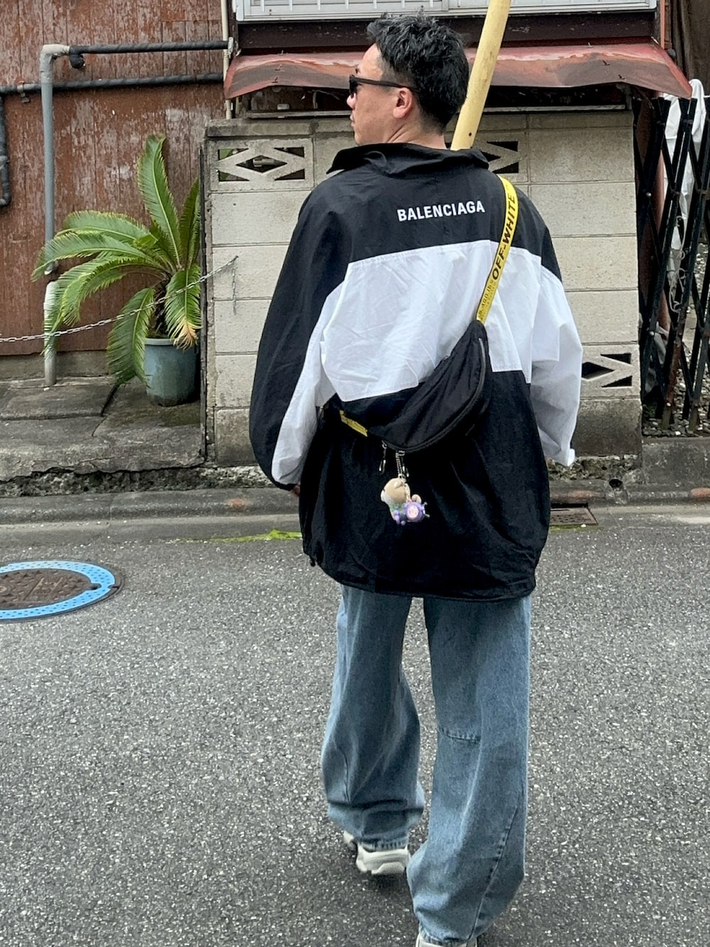 ブルー系のデニムパンツ、ブラック系のショルダーバッグ、ホワイト系のTシャツ/カットソーを着用したメンズの秋コーディネートの3枚目の写真