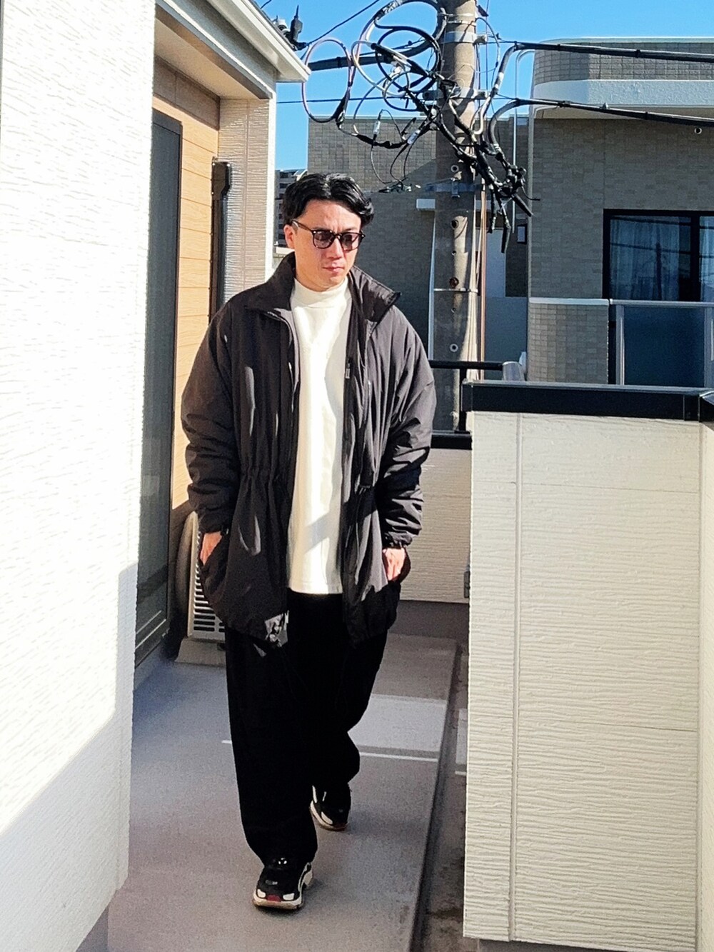 ベージュ系のスウェット、ブラック系のその他アウター、ブラック系のスラックスを着用したメンズの冬コーディネートの2枚目の写真