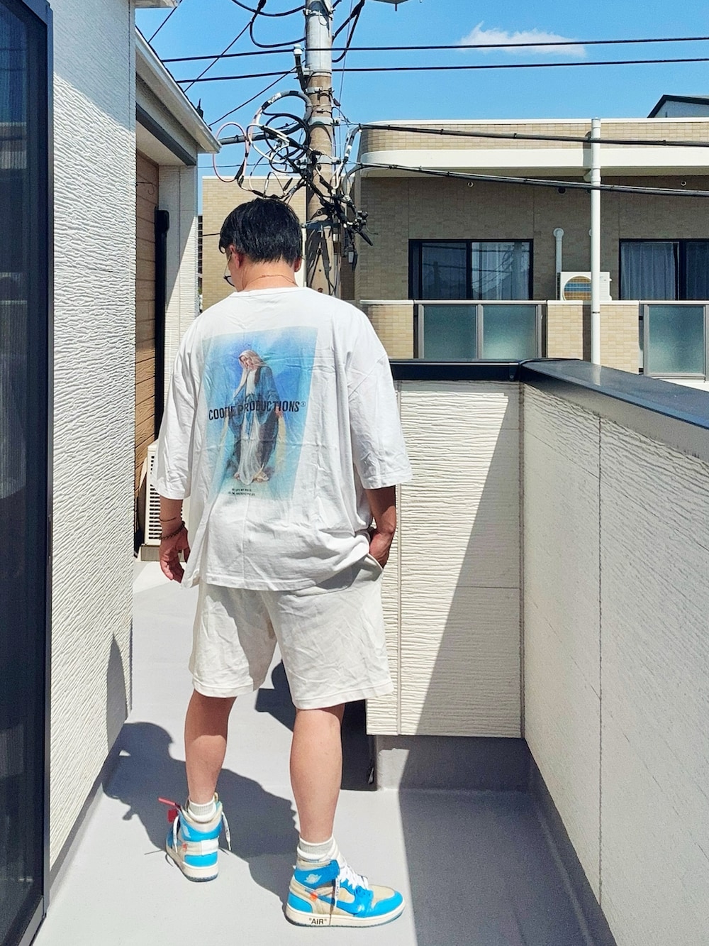 ホワイト系のTシャツ/カットソー、ホワイト系のパンツ、ブルー系のスニーカーを着用したメンズの春コーディネートの3枚目の写真