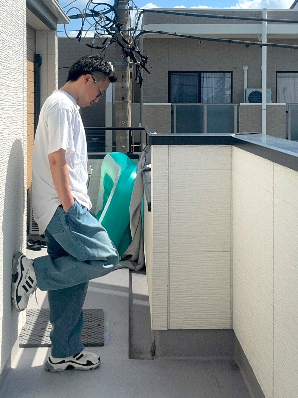 ホワイト系のTシャツ/カットソー、ブルー系のデニムパンツ、ホワイト系のシューズを着用したメンズの秋コーディネートの3枚目の写真