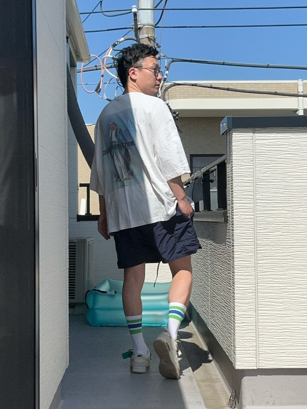 ホワイト系のTシャツ/カットソー、ブルー系のパンツ、ホワイト系のスニーカーを着用したメンズの夏コーディネートの3枚目の写真