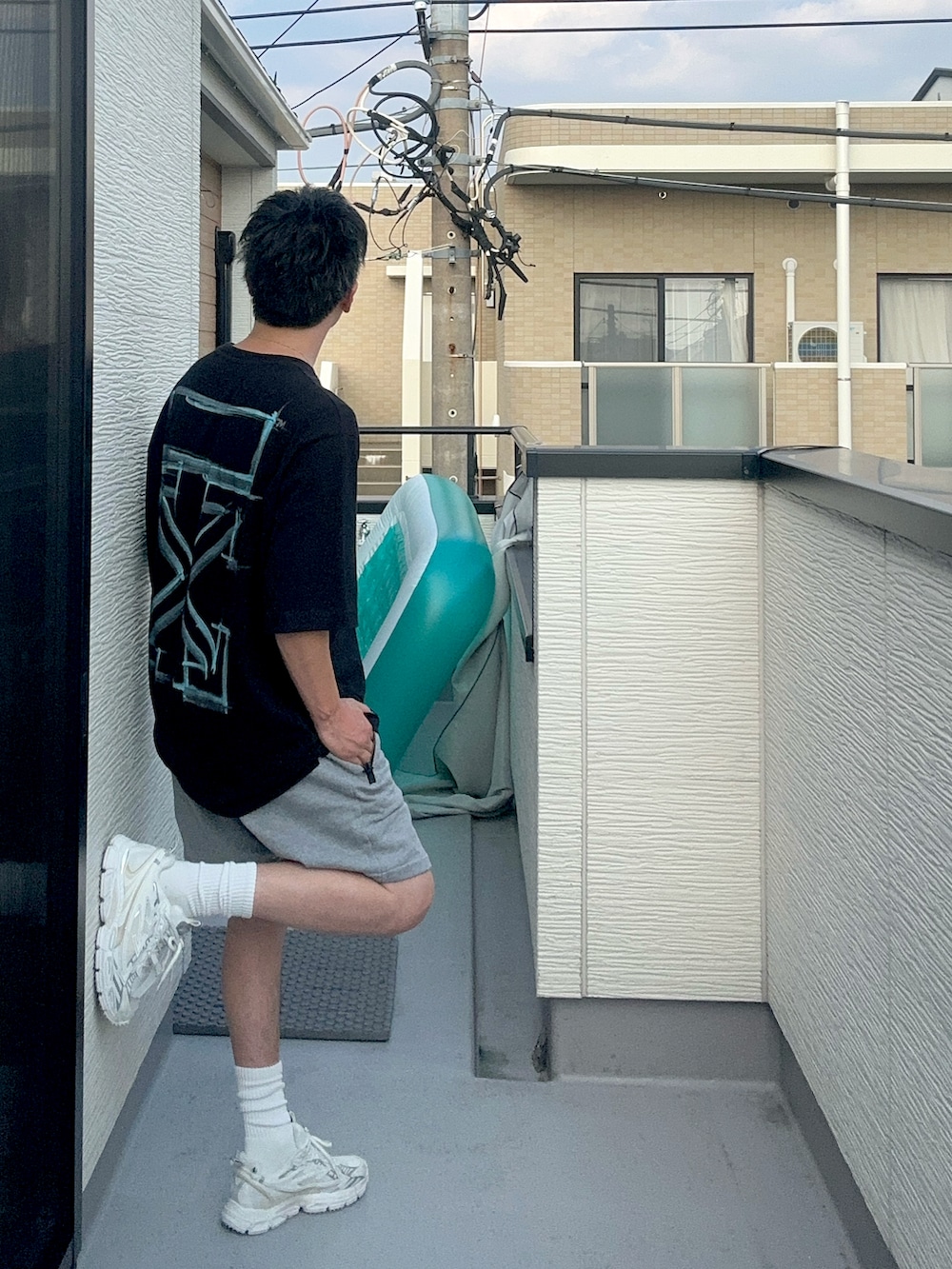 ブラック系のTシャツ/カットソー、グレー系のパンツ、ホワイト系のスニーカーを着用したメンズの夏コーディネートの2枚目の写真