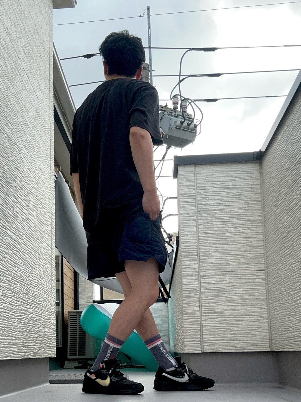 ブラック系のTシャツ/カットソー、ブルー系のパンツ、ブラック系のスニーカーを着用したメンズの夏コーディネートの5枚目の写真