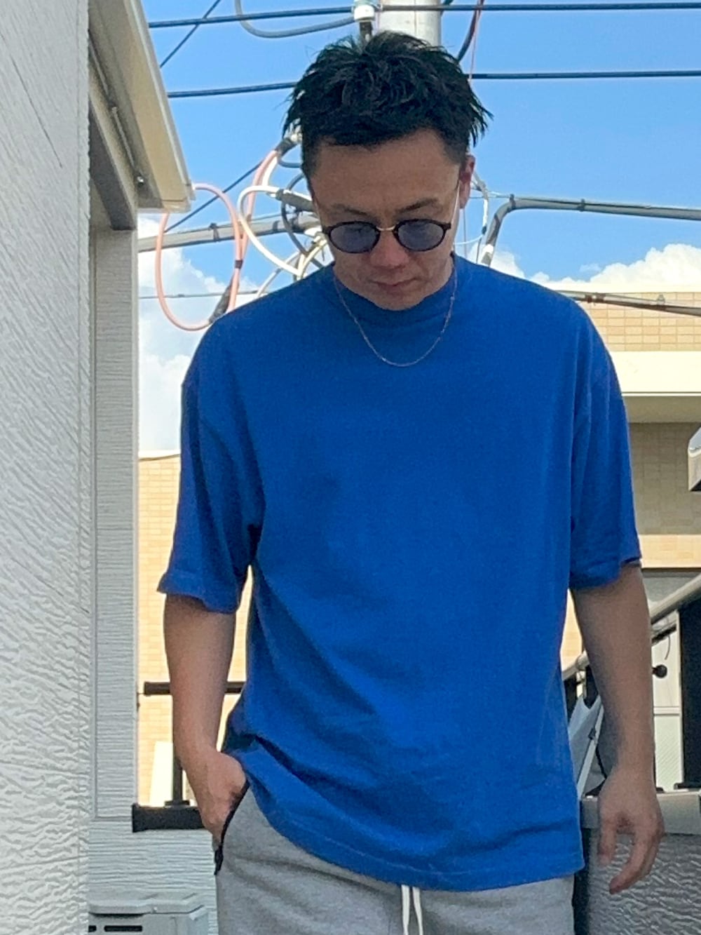 ブルー系のTシャツ/カットソー、グレー系のパンツ、ホワイト系のスニーカーを着用したメンズの夏コーディネートの2枚目の写真
