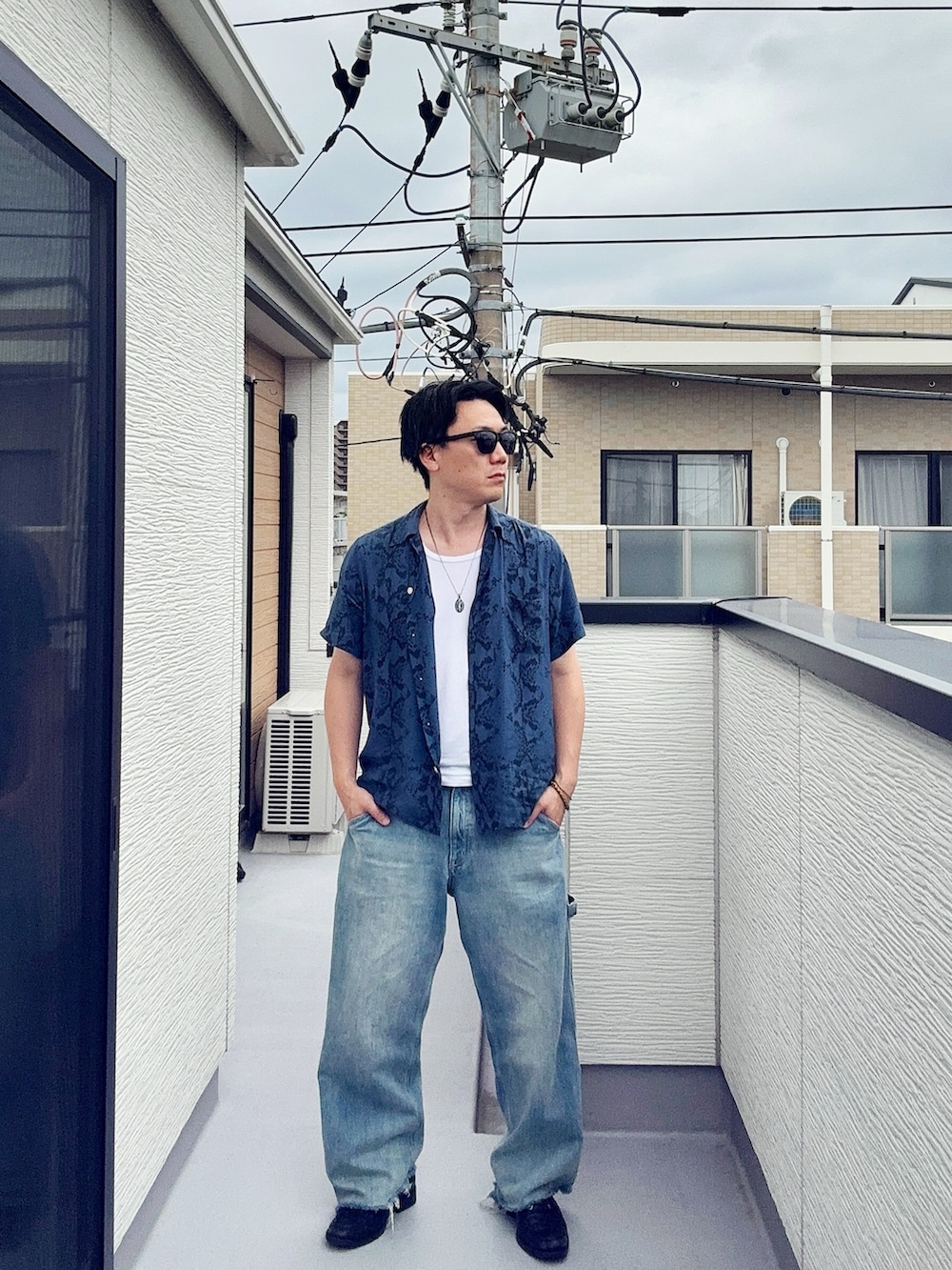 ブルー系のデニムパンツ、ブラック系のローファー、ホワイト系のタンクトップを着用したメンズの夏コーディネートの2枚目の写真