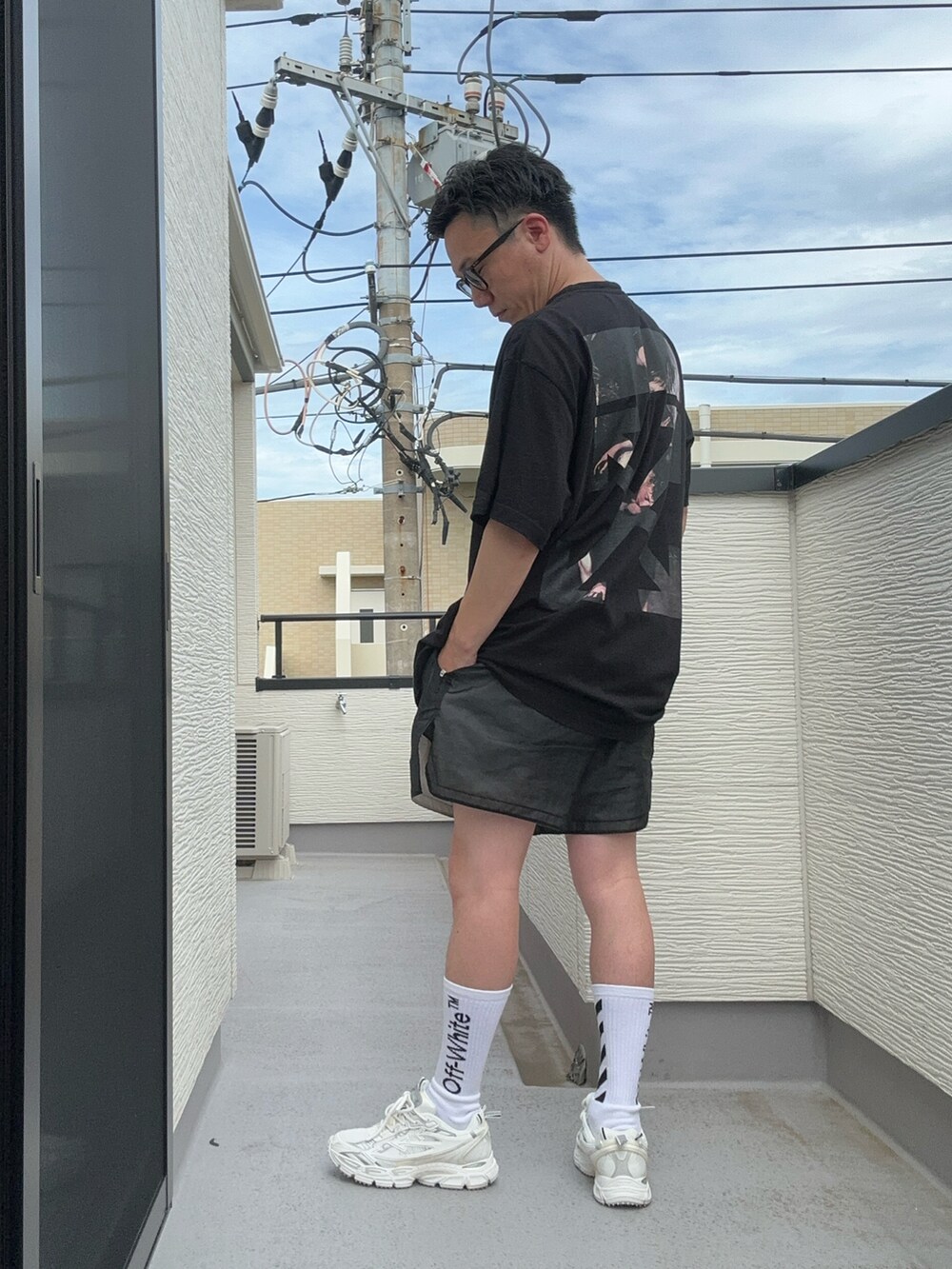 ブラック系のTシャツ/カットソー、ホワイト系のスニーカー、ブラック系のパンツを着用したメンズの夏コーディネートの2枚目の写真