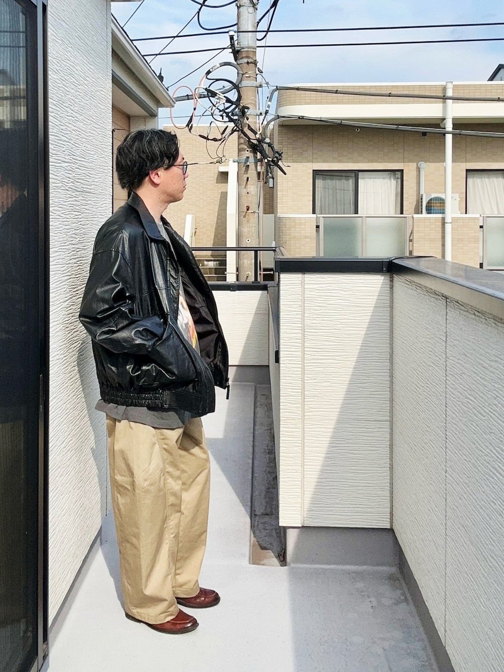 ブラック系のブルゾン、ブラック系のTシャツ/カットソー、ベージュ系のパンツを着用したメンズの秋コーディネートの4枚目の写真