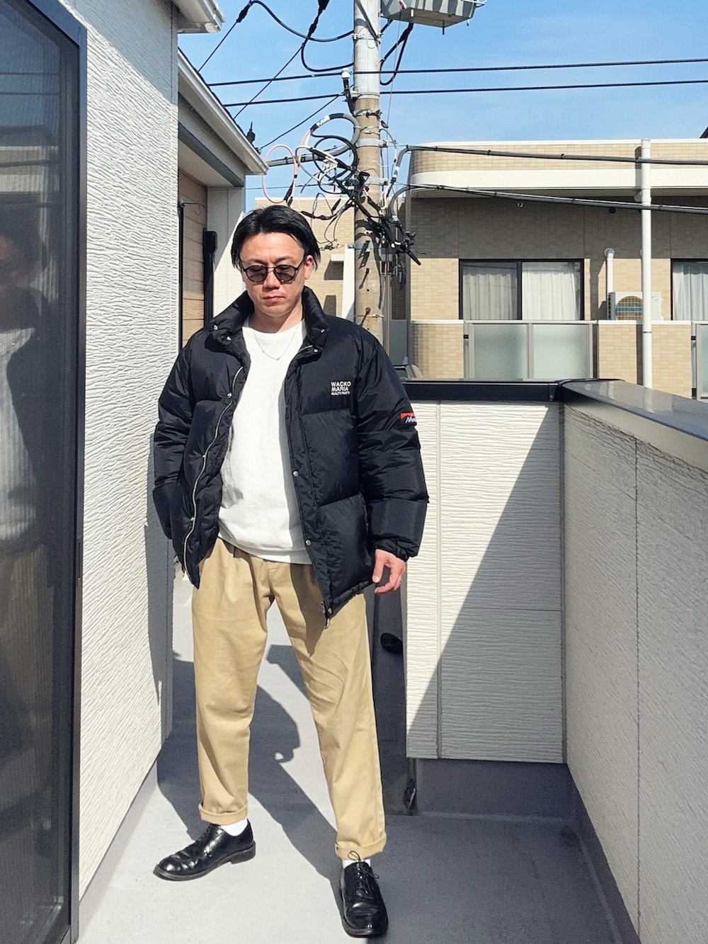 グリーン系のチノパンツ、ブラック系のその他アウター、ホワイト系のスウェットを着用したメンズの春コーディネートの2枚目の写真