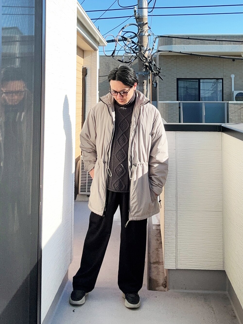 ブラック系のニット/セーター、ベージュ系のその他アウター、ブラック系のスニーカーを着用したメンズの冬コーディネートの3枚目の写真