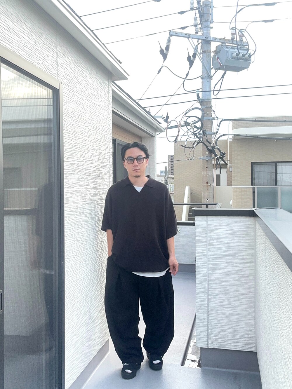 ブラック系のポロシャツ、ブラック系のスウェットパンツ、ブラック系のサンダルを着用したメンズの夏コーディネートの2枚目の写真