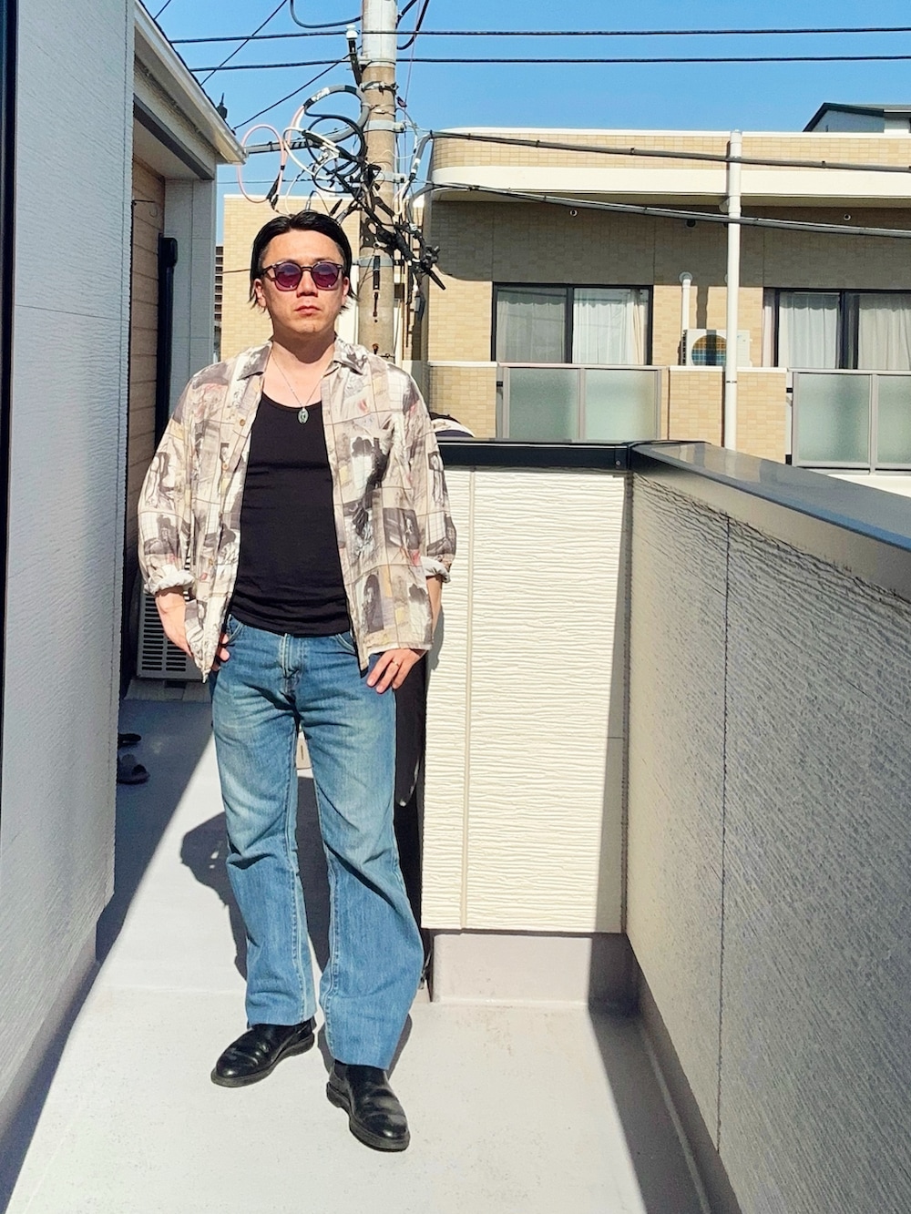 ブルー系のデニムパンツ、ブラック系のタンクトップ、ベージュ系のシャツ/ブラウスを着用したメンズの春コーディネートの2枚目の写真
