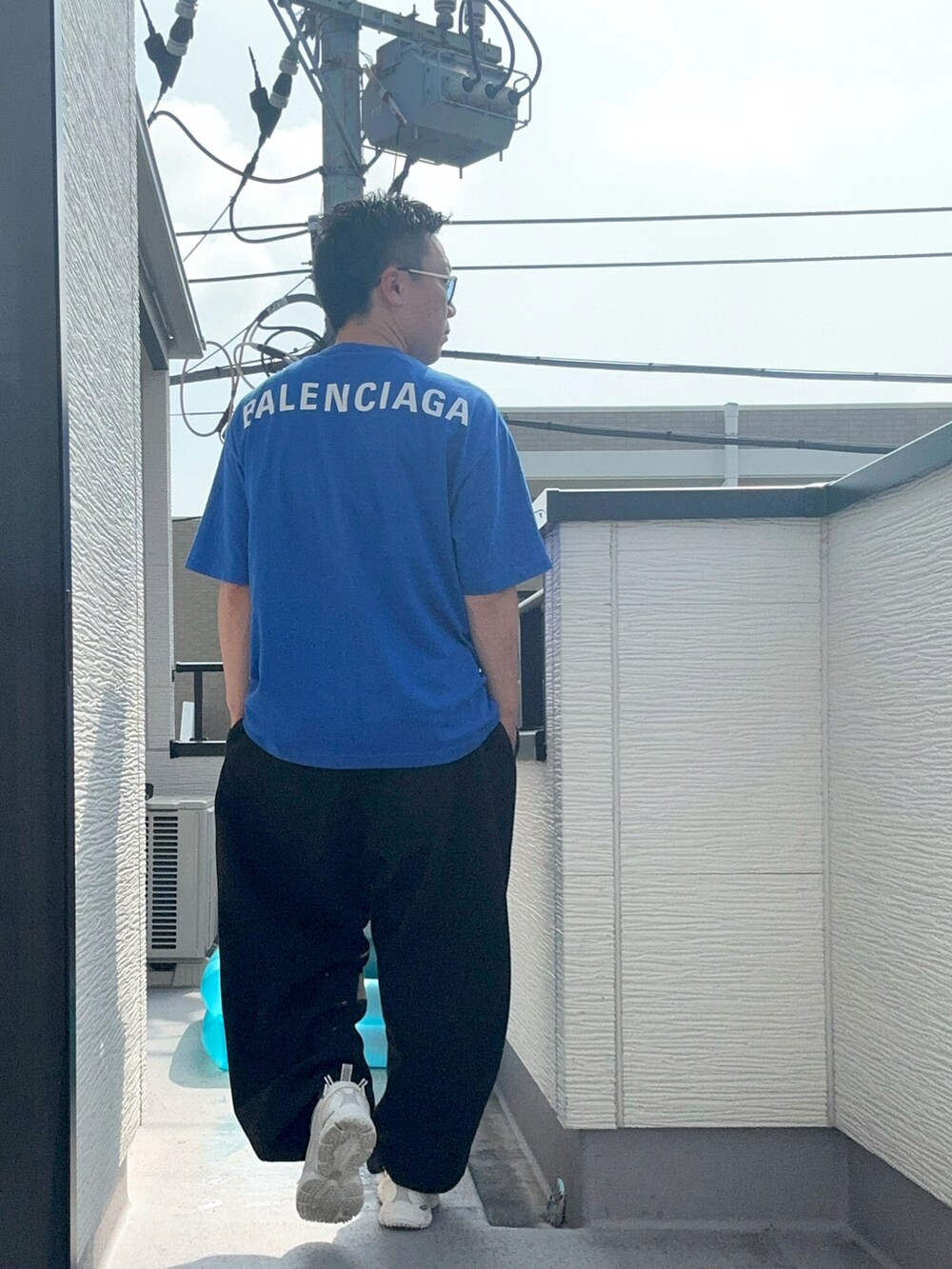 ブラック系のスウェットパンツ、ブルー系のTシャツ/カットソー、ホワイト系のスニーカーを着用したメンズの夏コーディネートの2枚目の写真