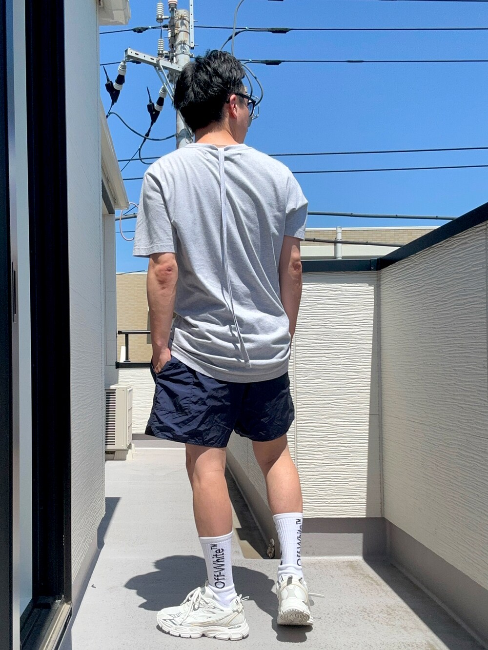グレー系のTシャツ/カットソー、ブルー系のパンツ、ホワイト系のスニーカーを着用したメンズの夏コーディネートの4枚目の写真