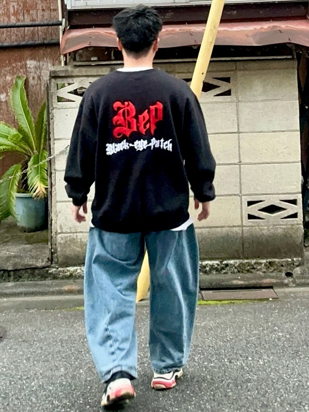 ブルー系のデニムパンツ、ブラック系のスウェット、ブラック系のスニーカーを着用したメンズの秋コーディネートの5枚目の写真