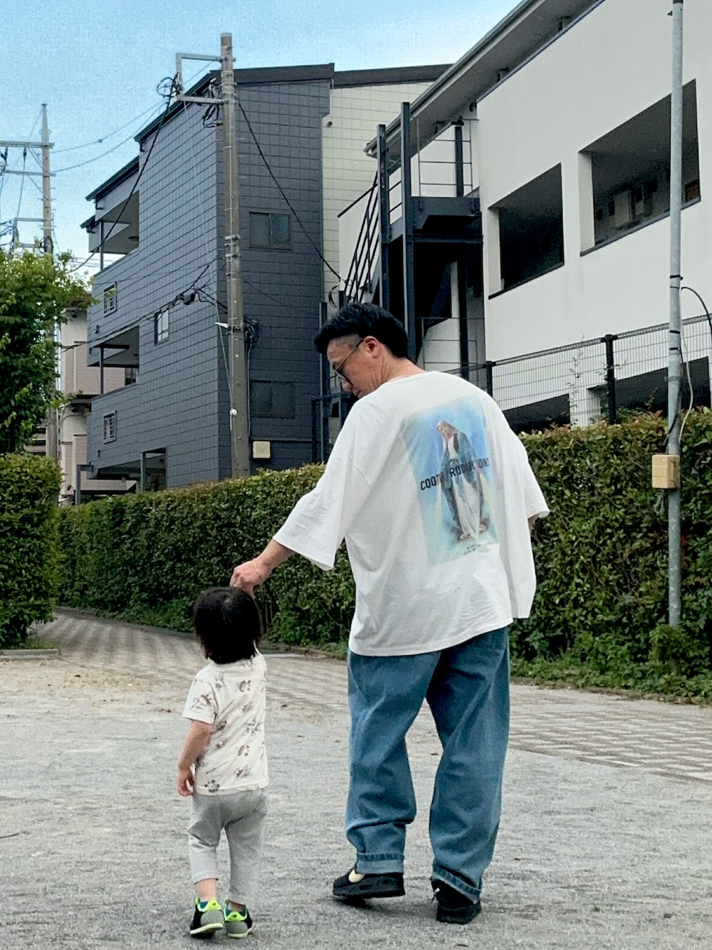 ホワイト系のTシャツ/カットソー、ブルー系のデニムパンツ、ブラック系のスニーカーを着用したメンズの夏コーディネートの2枚目の写真