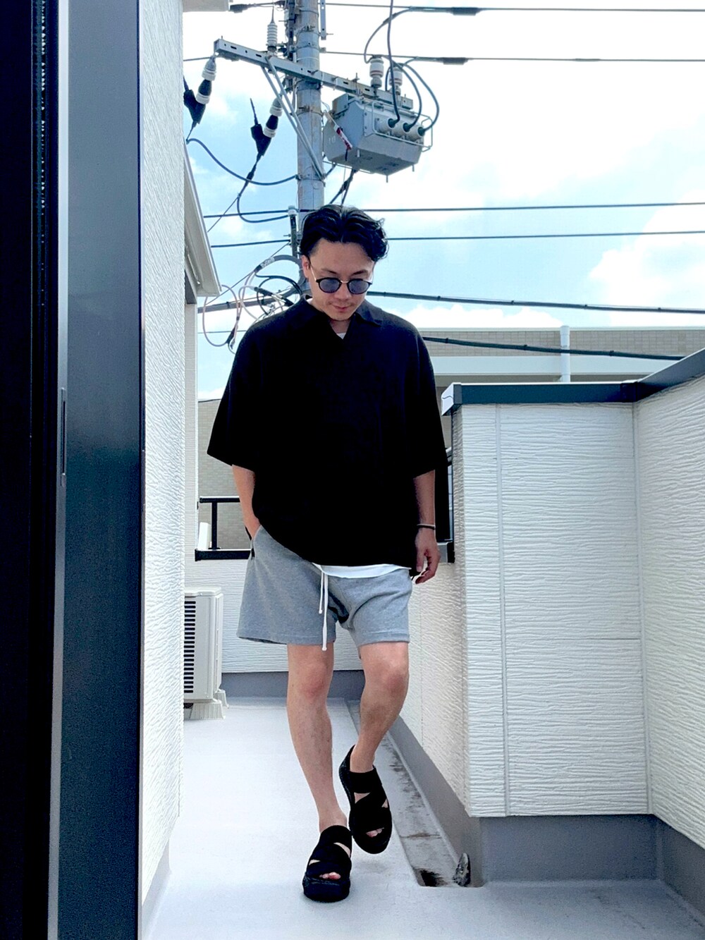 ブラック系のポロシャツ、グレー系のパンツ、ホワイト系のTシャツ/カットソーを着用したメンズの夏コーディネートの2枚目の写真