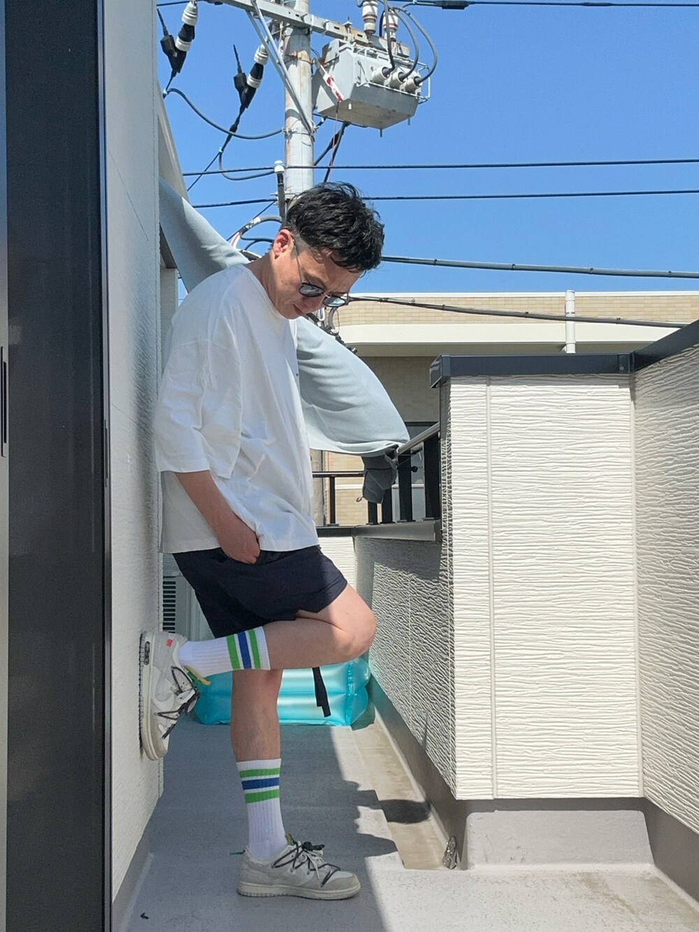 ホワイト系のTシャツ/カットソー、ブルー系のパンツ、ホワイト系のスニーカーを着用したメンズの夏コーディネートの2枚目の写真