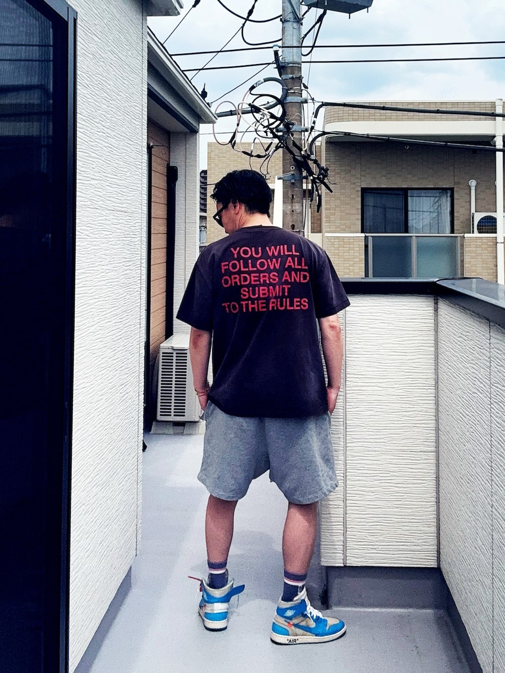 ブラック系のTシャツ/カットソー、グレー系のパンツ、ブルー系のスニーカーを着用したメンズの夏コーディネートの3枚目の写真