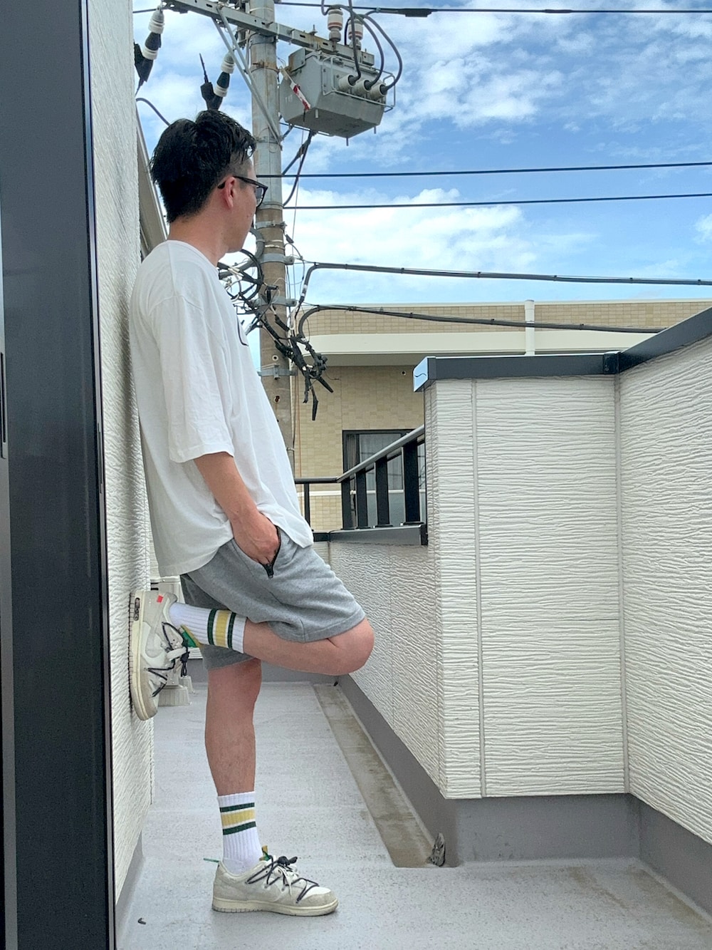 ホワイト系のTシャツ/カットソー、グレー系のパンツ、ホワイト系のスニーカーを着用したメンズの夏コーディネートの3枚目の写真