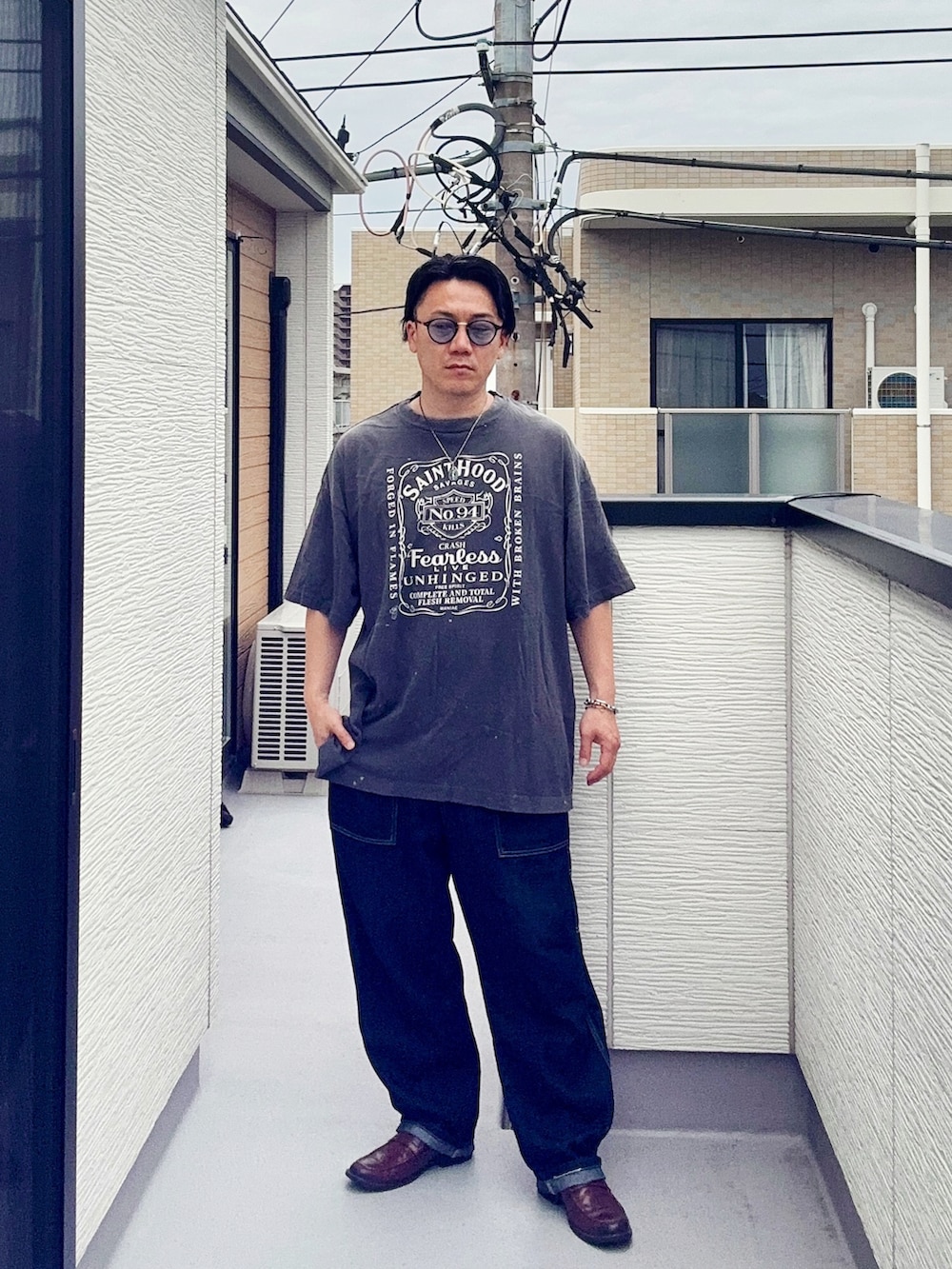 ブルー系のデニムパンツ、ブラック系のTシャツ/カットソー、ブラウン系のローファーを着用したメンズの夏コーディネートの3枚目の写真