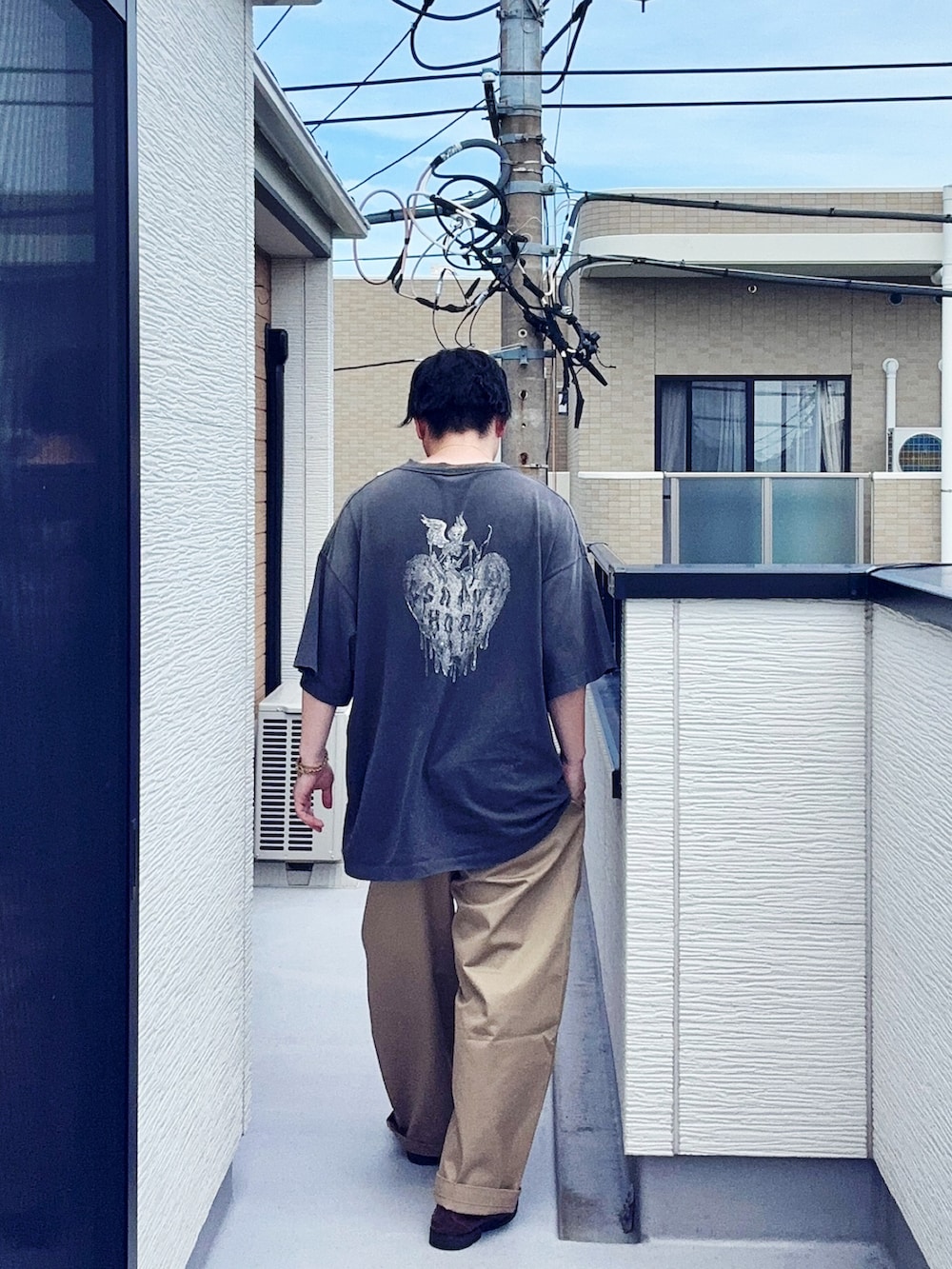 ブラック系のローファー、ブラック系のTシャツ/カットソー、ベージュ系のチノパンツを着用したメンズの夏コーディネートの3枚目の写真