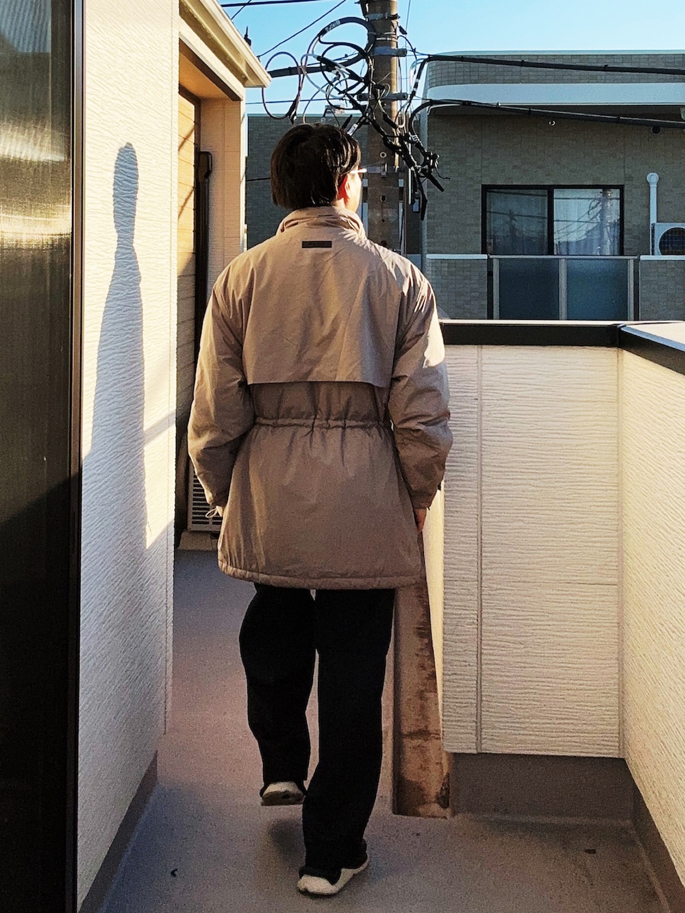 ベージュ系のその他アウター、ブルー系のスラックス、ブラック系のスニーカーを着用したメンズの冬コーディネートの3枚目の写真