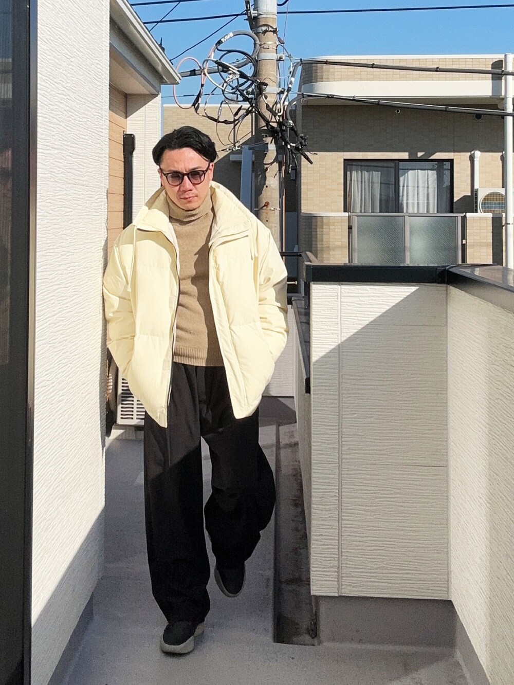 ベージュ系のニット/セーター、ベージュ系のダウンジャケット/コート、ブラック系のスラックスを着用したメンズの冬コーディネートの2枚目の写真