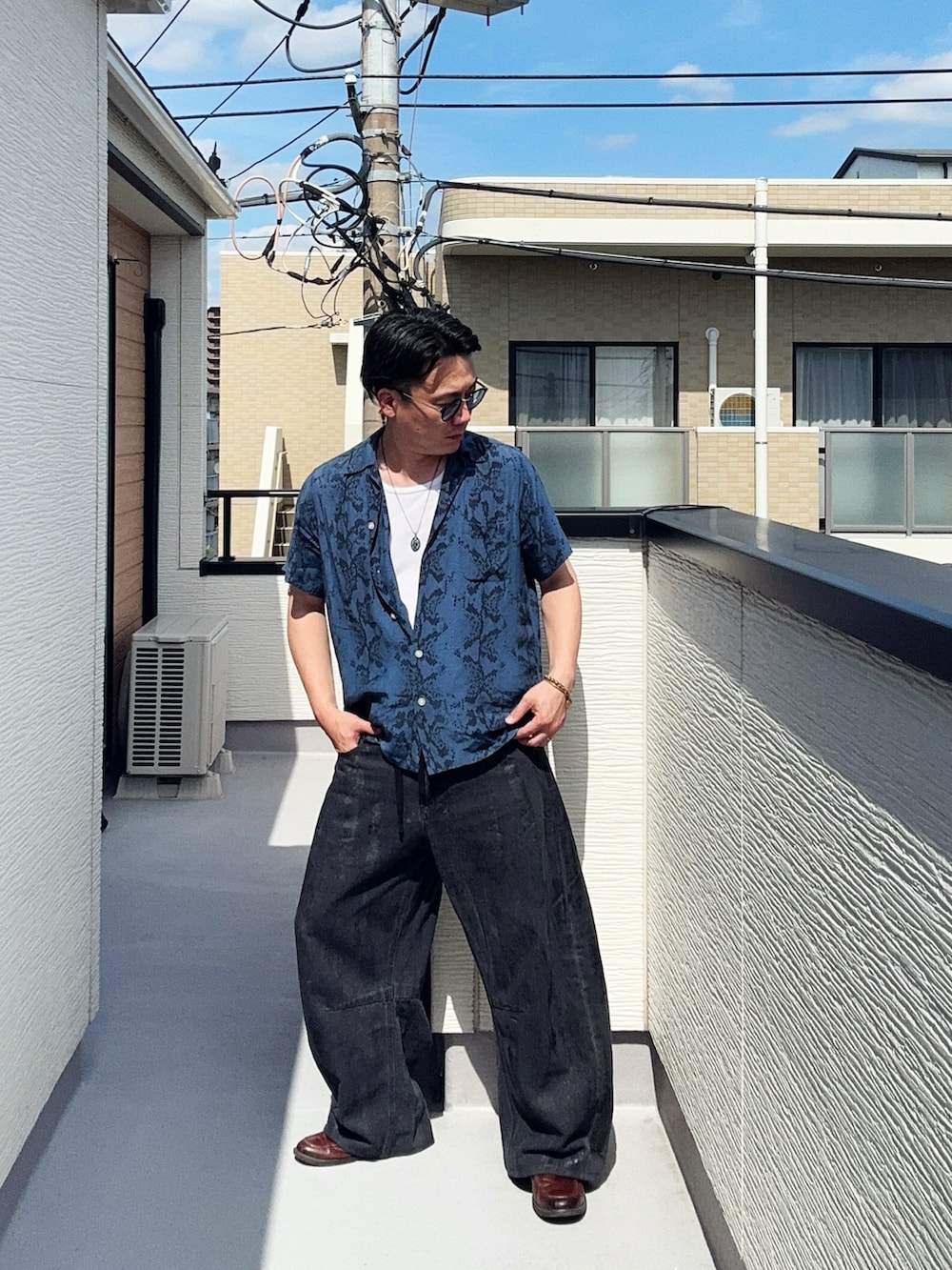 ブラック系のデニムパンツ、ブルー系のシャツ/ブラウス、ブラウン系のローファーを着用したメンズの夏コーディネートの2枚目の写真