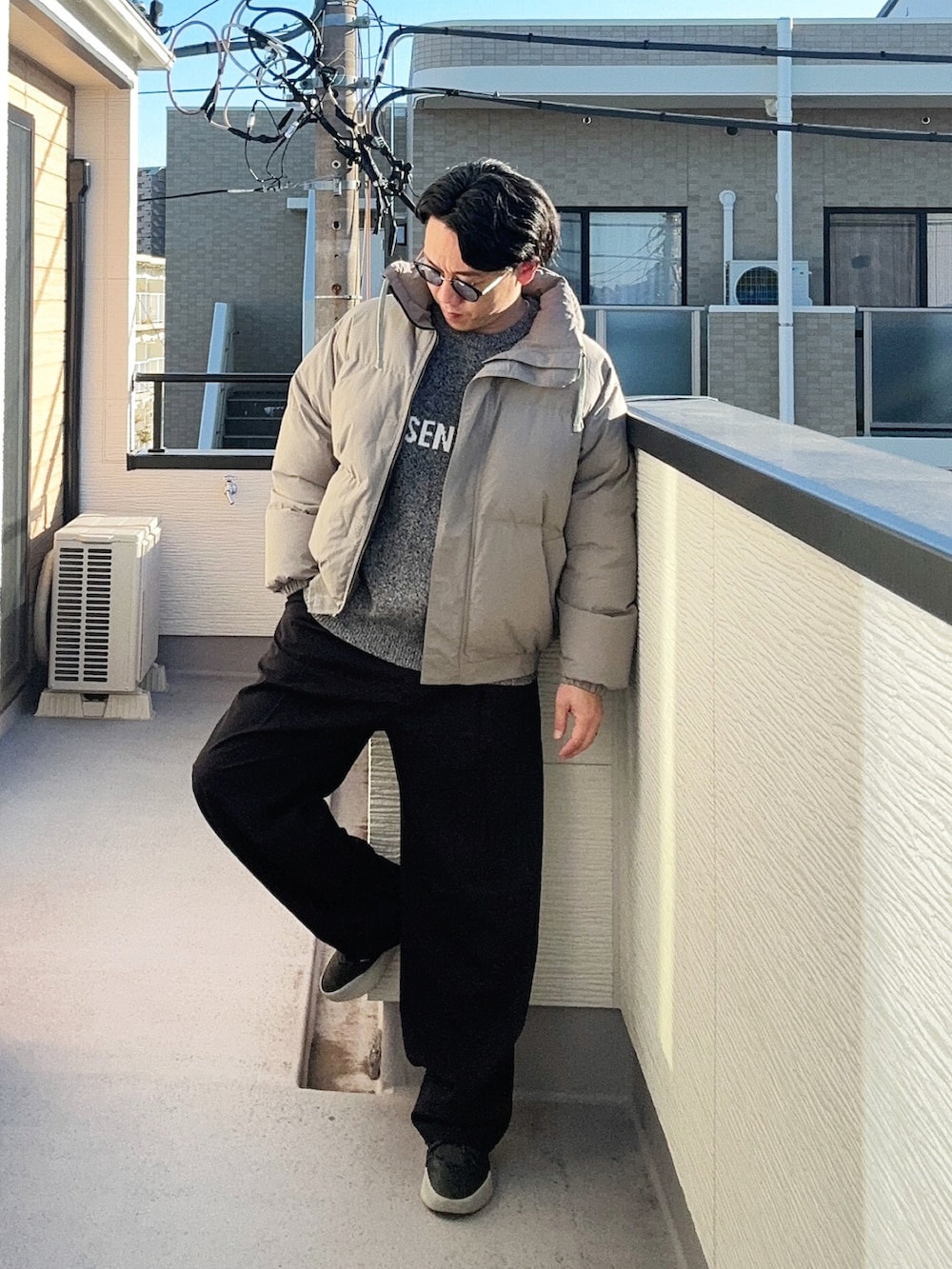 グレー系のニット/セーター、グレー系のダウンジャケット/コート、ブラック系のスラックスを着用したメンズの冬コーディネートの3枚目の写真