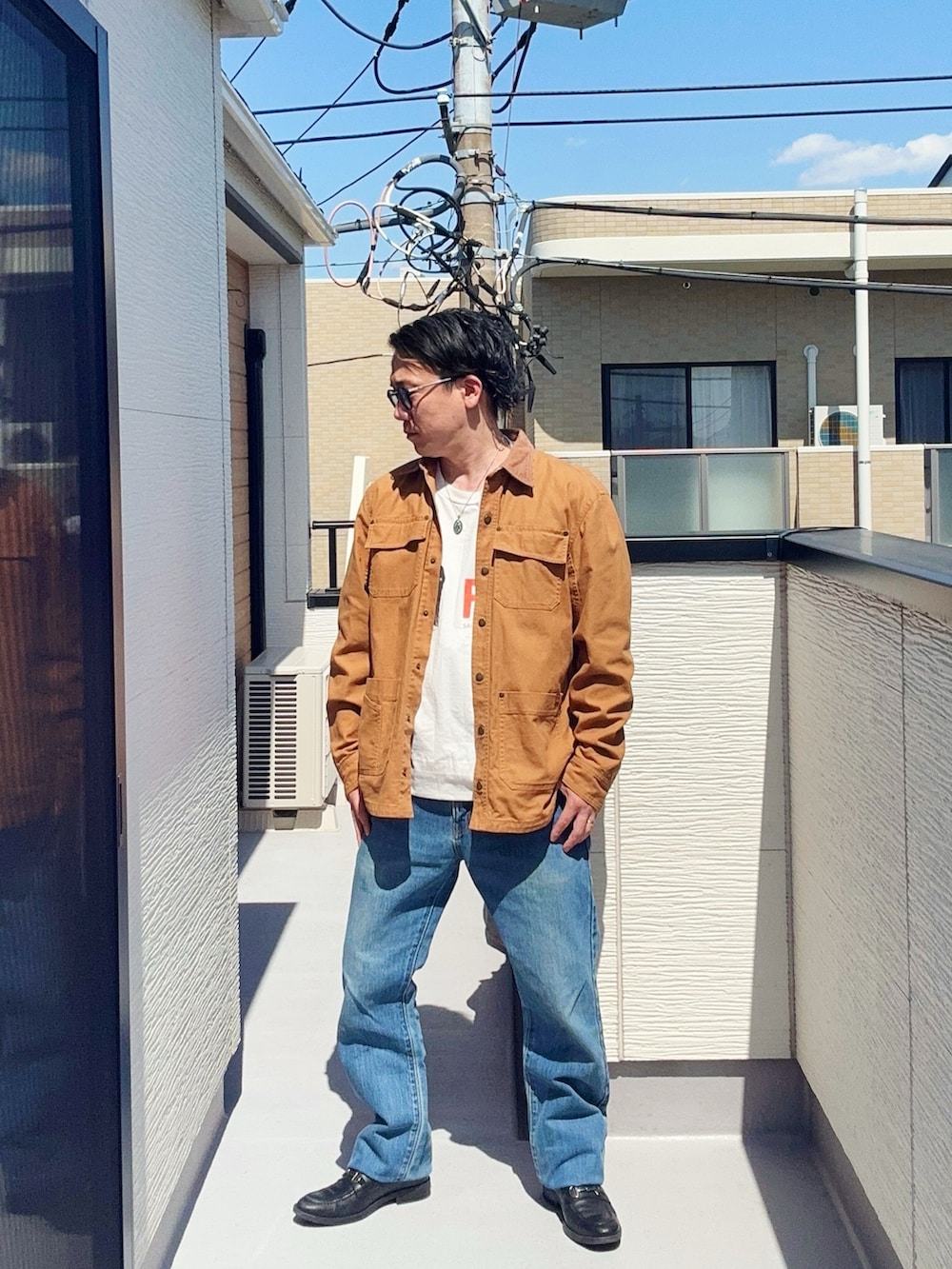 ブルー系のデニムパンツ、ブラック系のローファー、ホワイト系のTシャツ/カットソーを着用したメンズの春コーディネートの2枚目の写真