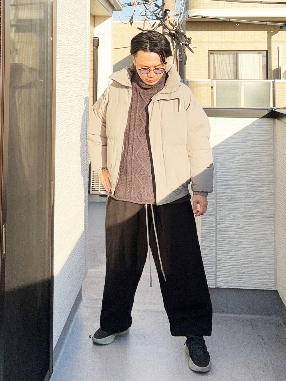 グレー系のダウンジャケット/コート、ブラック系のスウェットパンツ、ブラック系のニット/セーターを着用したメンズの冬コーディネートの2枚目の写真