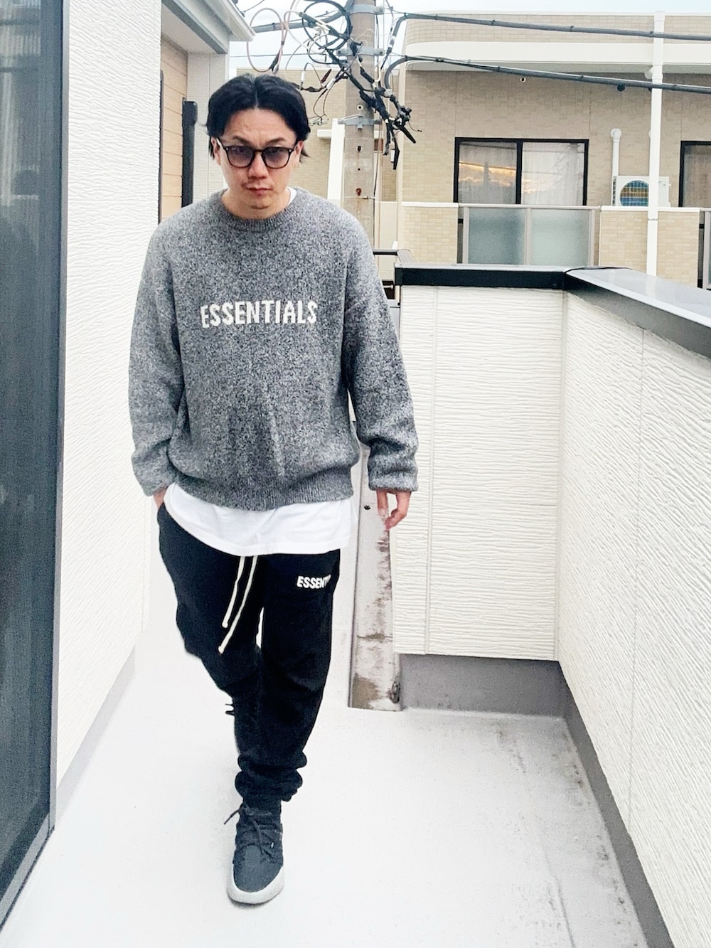 グレー系のニット/セーター、ホワイト系のTシャツ/カットソー、ブラック系のスウェットパンツを着用したメンズの秋コーディネートの2枚目の写真