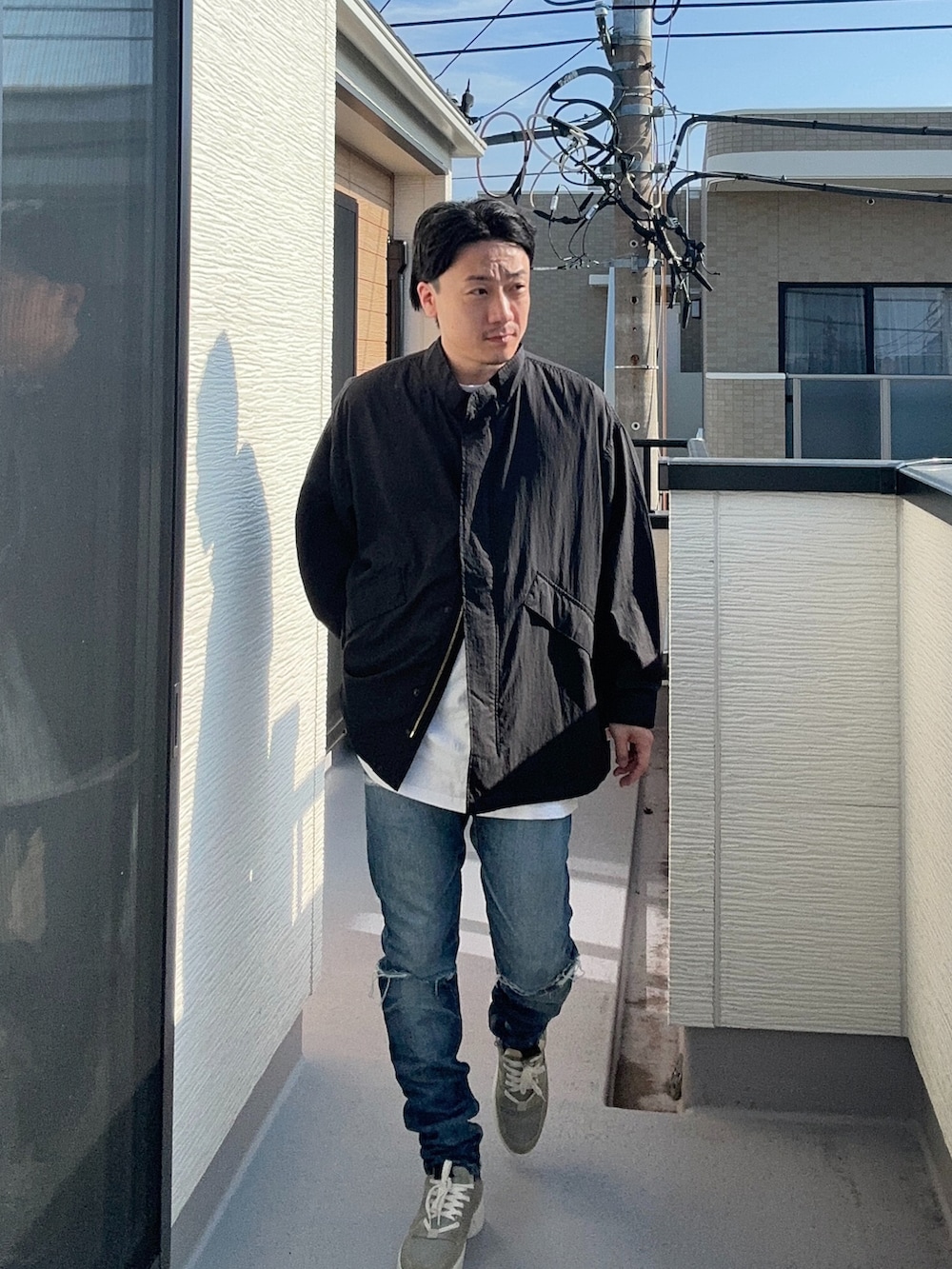 ブラック系のブルゾン、ホワイト系のTシャツ/カットソー、ブルー系のデニムパンツを着用したメンズの秋コーディネートの3枚目の写真