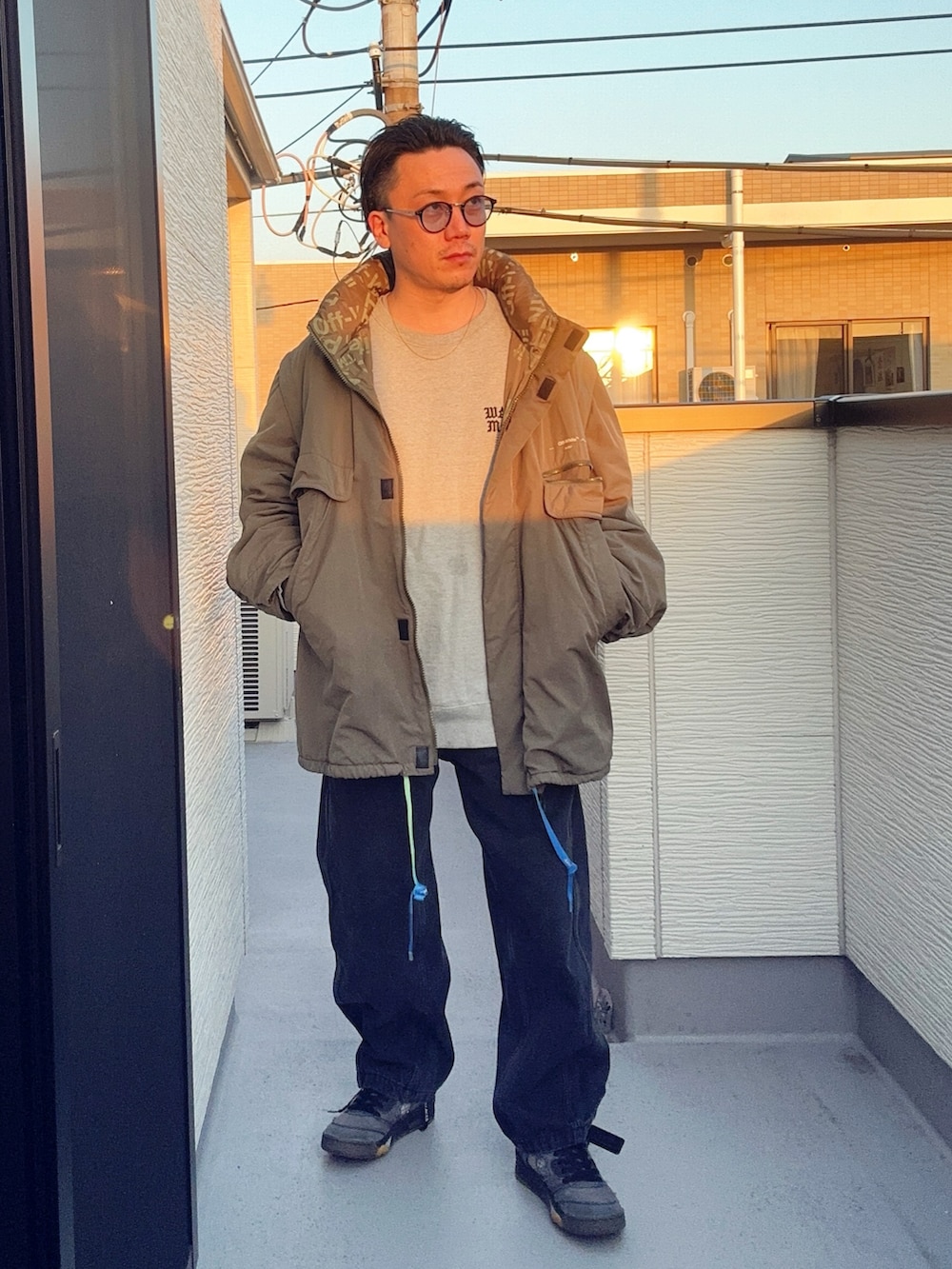 ブラック系のデニムパンツ、グレー系のスウェット、グリーン系のミリタリージャケットを着用したメンズの冬コーディネートの2枚目の写真