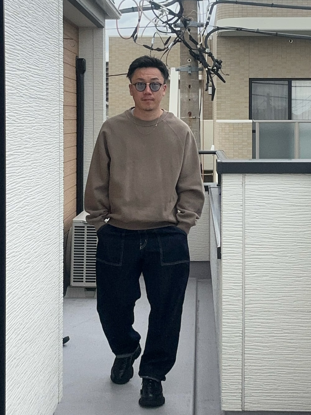 ベージュ系のスウェット、ブルー系のデニムパンツ、ブラック系のシューズを着用したメンズの秋コーディネートの3枚目の写真