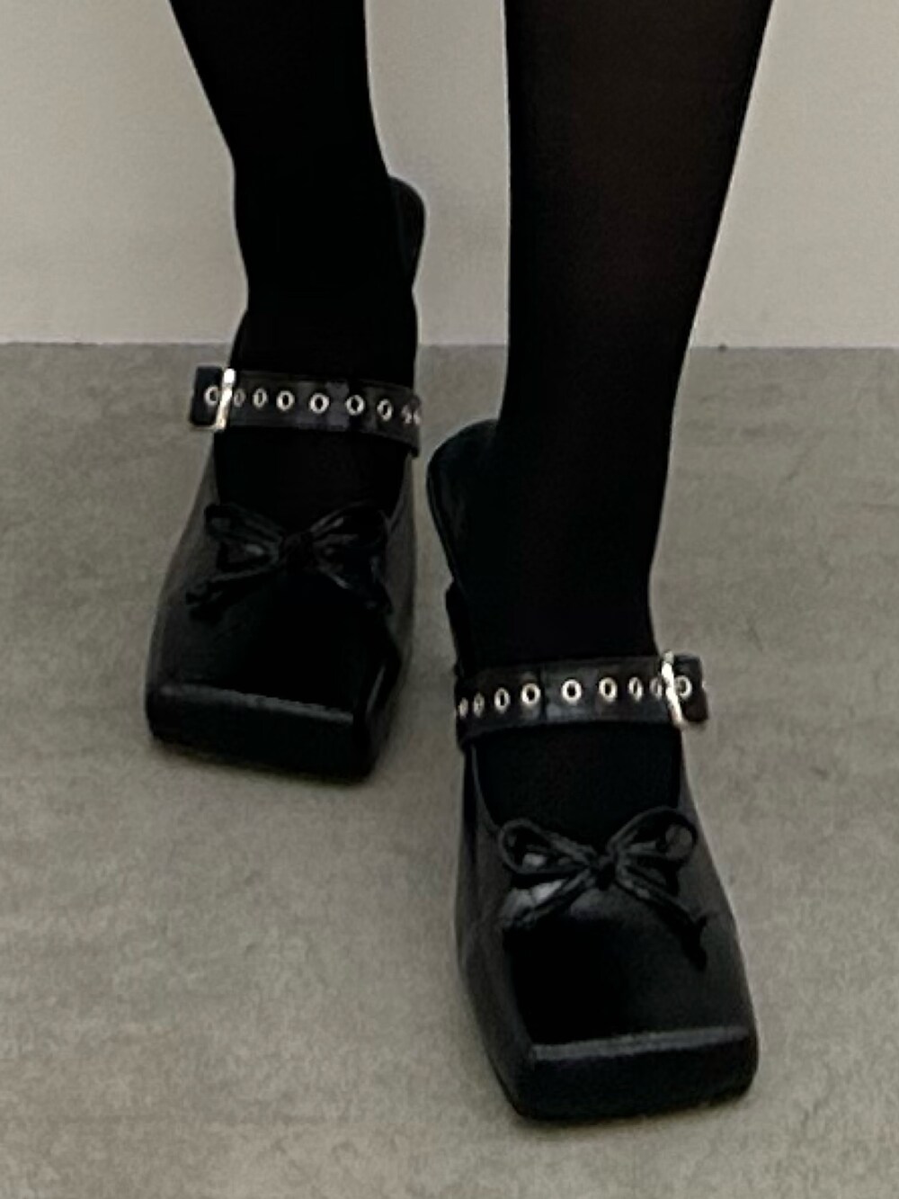 ブラック系のパンプス、ホワイト系のワンピース、ブラック系のベストを着用したレディースの冬コーディネートの7枚目の写真