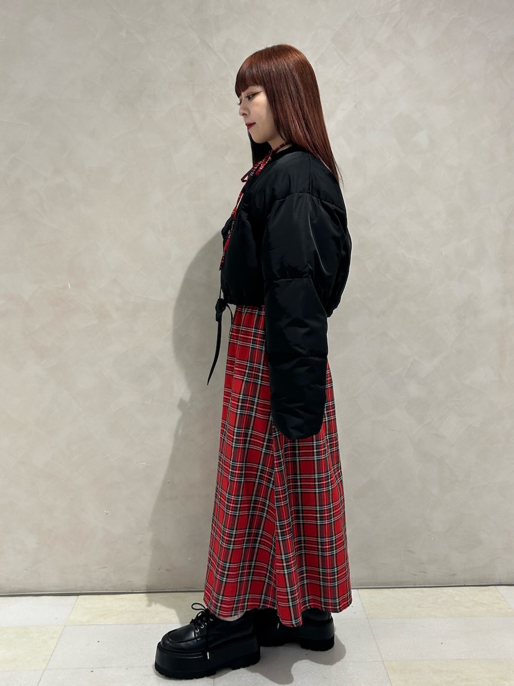 レッド系のワンピース、ブラック系のブルゾン、ブラック系のドレスシューズを着用したレディースの冬コーディネートの2枚目の写真
