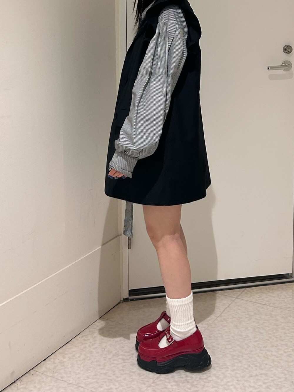 ブラック系のシャツ/ブラウス、ブラック系のワンピース、レッド系のスニーカーを着用したレディースの春コーディネートの2枚目の写真