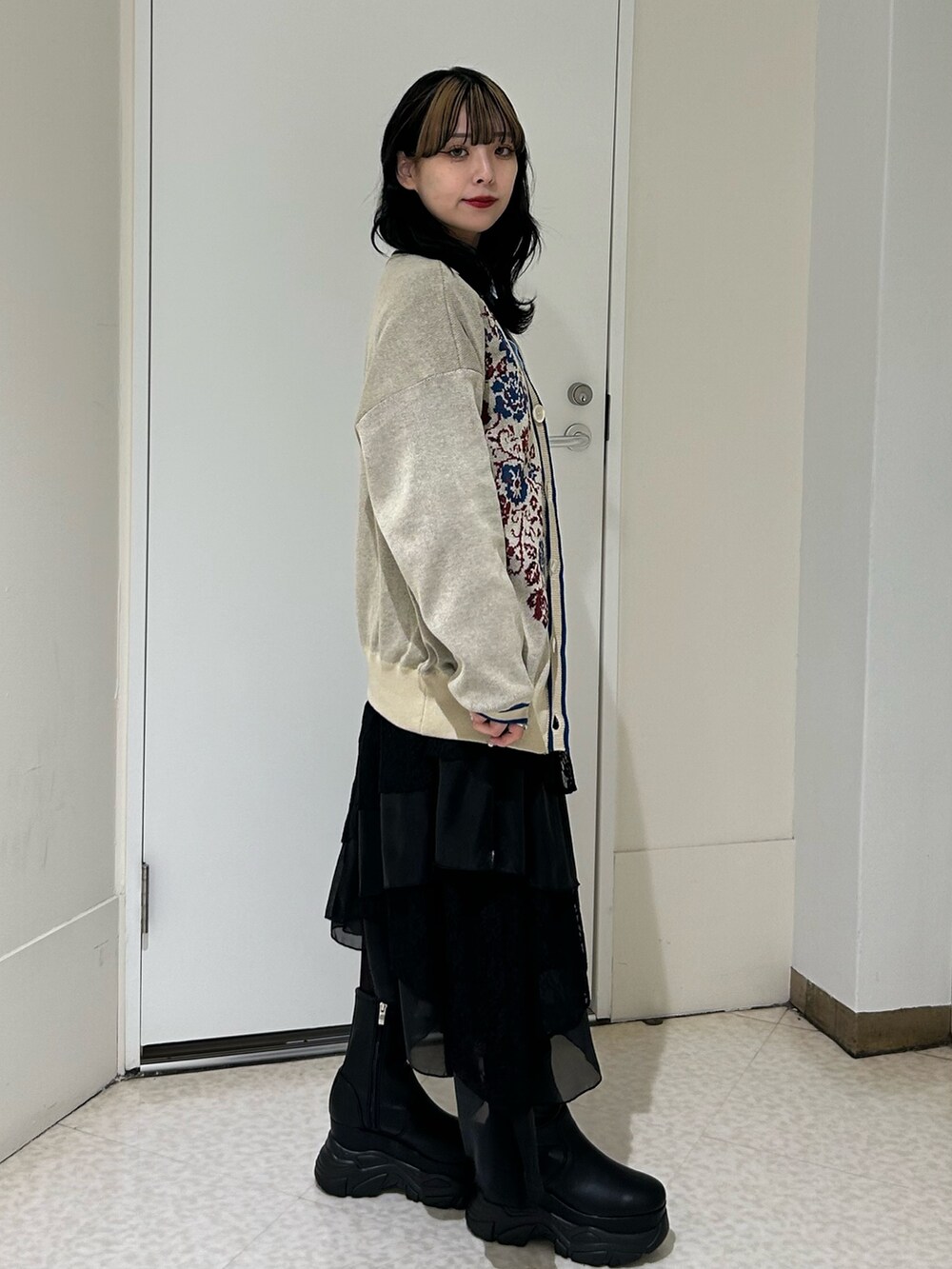 ホワイト系のニット/セーター、ブルー系のシャツ/ブラウス、ブラック系のブーツを着用したレディースの冬コーディネートの2枚目の写真