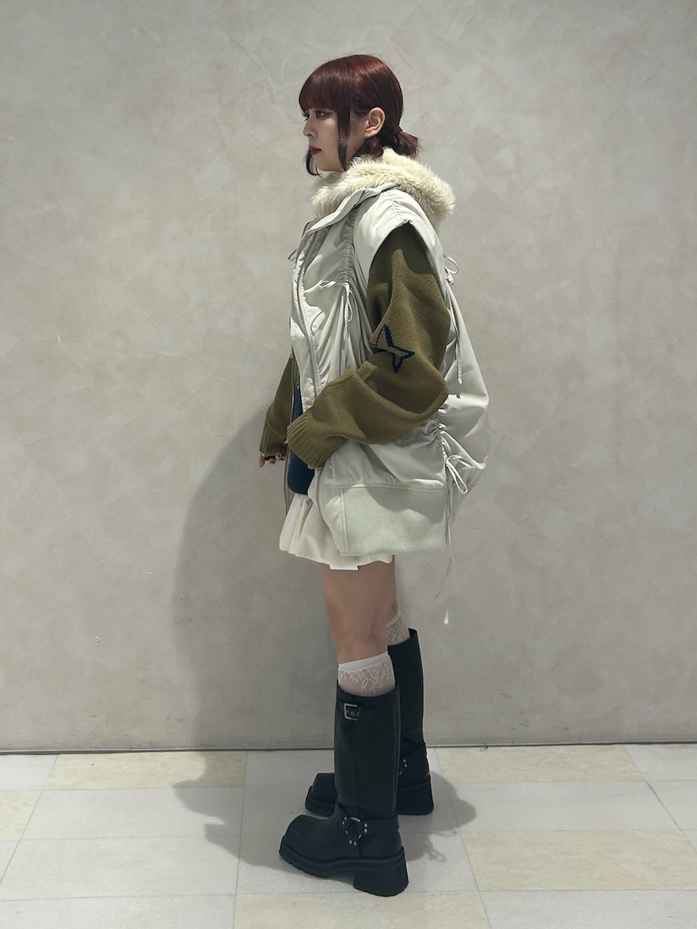 ブルー系のニット/セーター、ホワイト系のスカート、ホワイト系のダウンベストを着用したレディースの冬コーディネートの3枚目の写真