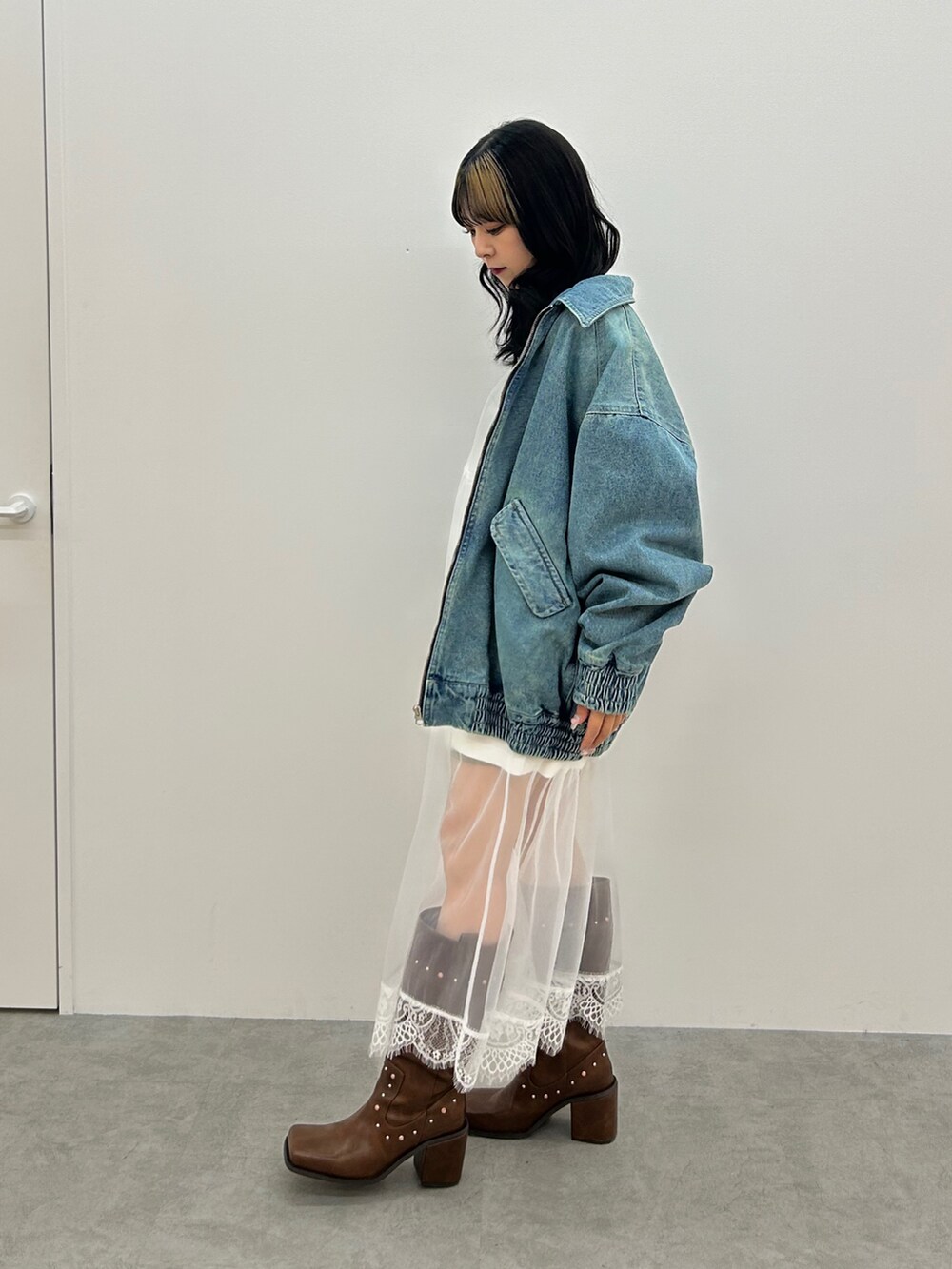 ブルー系のデニムジャケット、ホワイト系のワンピース、ブラウン系のブーツを着用したレディースの冬コーディネートの2枚目の写真