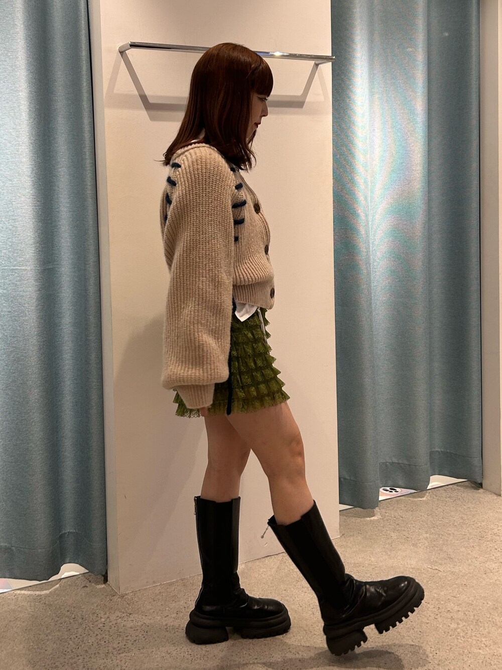 ホワイト系のカーディガン/ボレロ、グリーン系のその他パンツ、ブラック系のブーツを着用したレディースの冬コーディネートの2枚目の写真