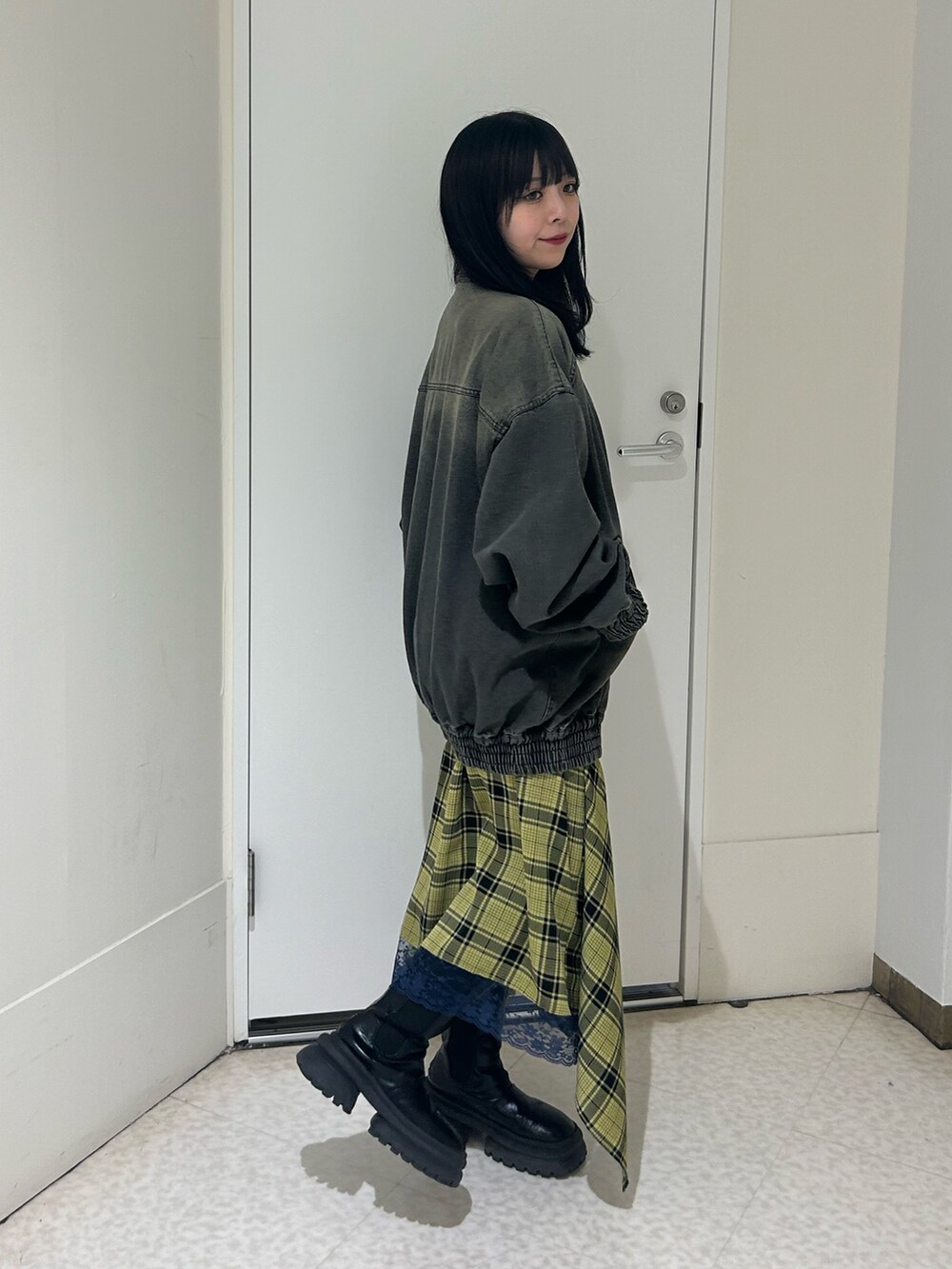 ブラック系のデニムジャケット、イエロー系のスカート、ブラック系のブーツを着用したレディースの春コーディネートの2枚目の写真